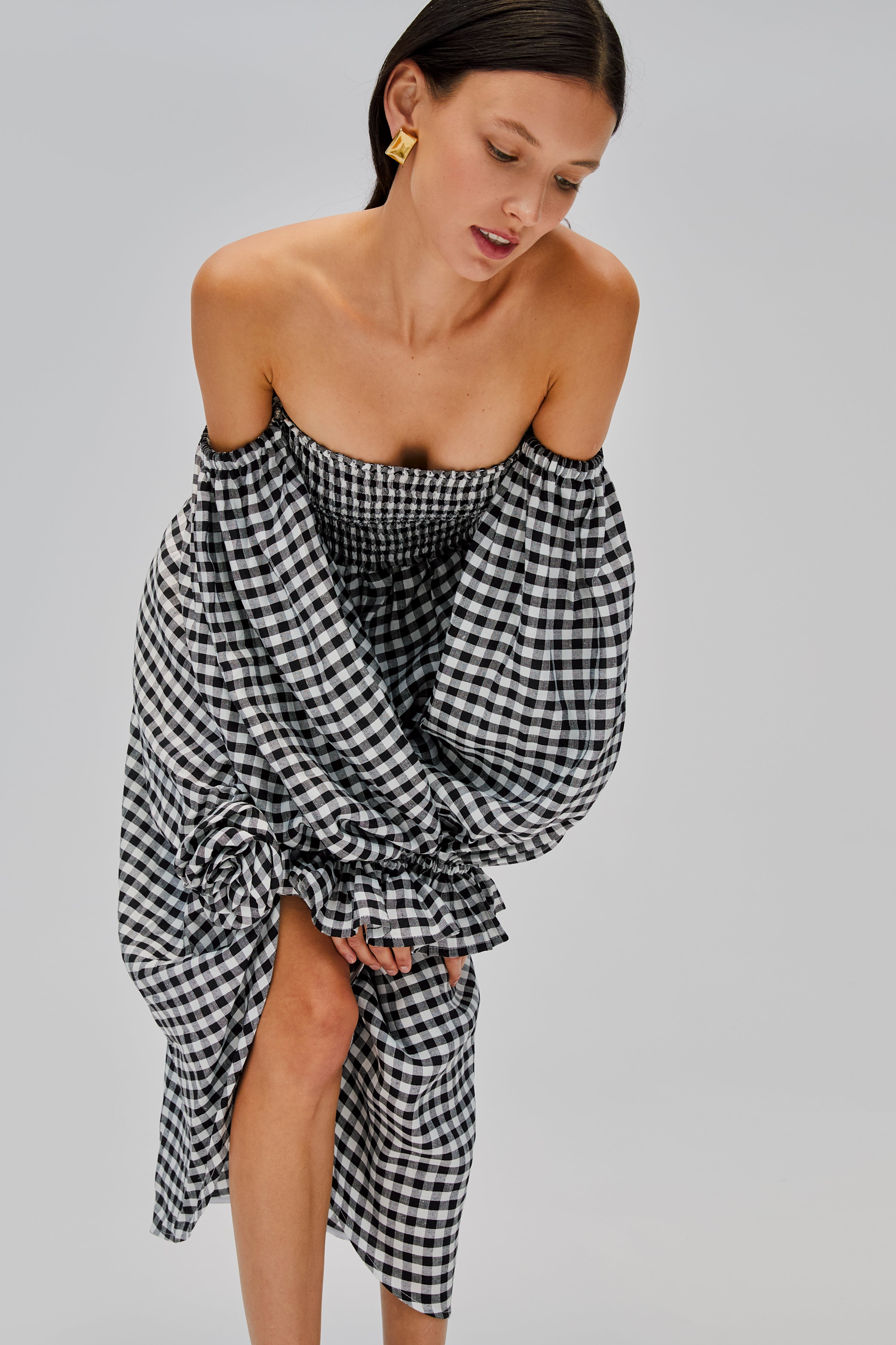 woman-wearing-black-gingham-off-shoulder-dress-with-rose-detail-front-split-long-sleeves