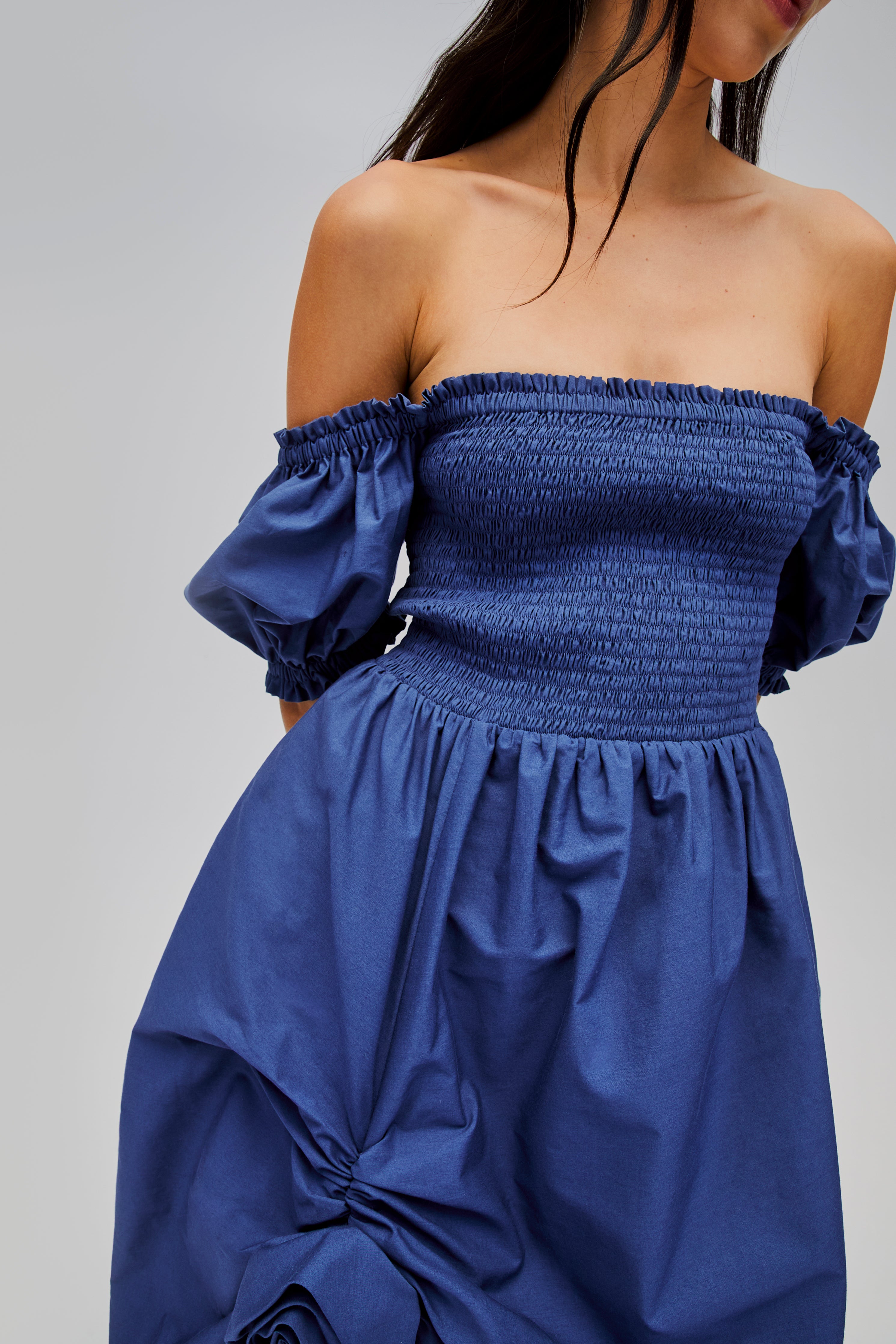 woman-wearing-navy-shirred-bodice-dress-with-short-sleeves-off-the-shoulder