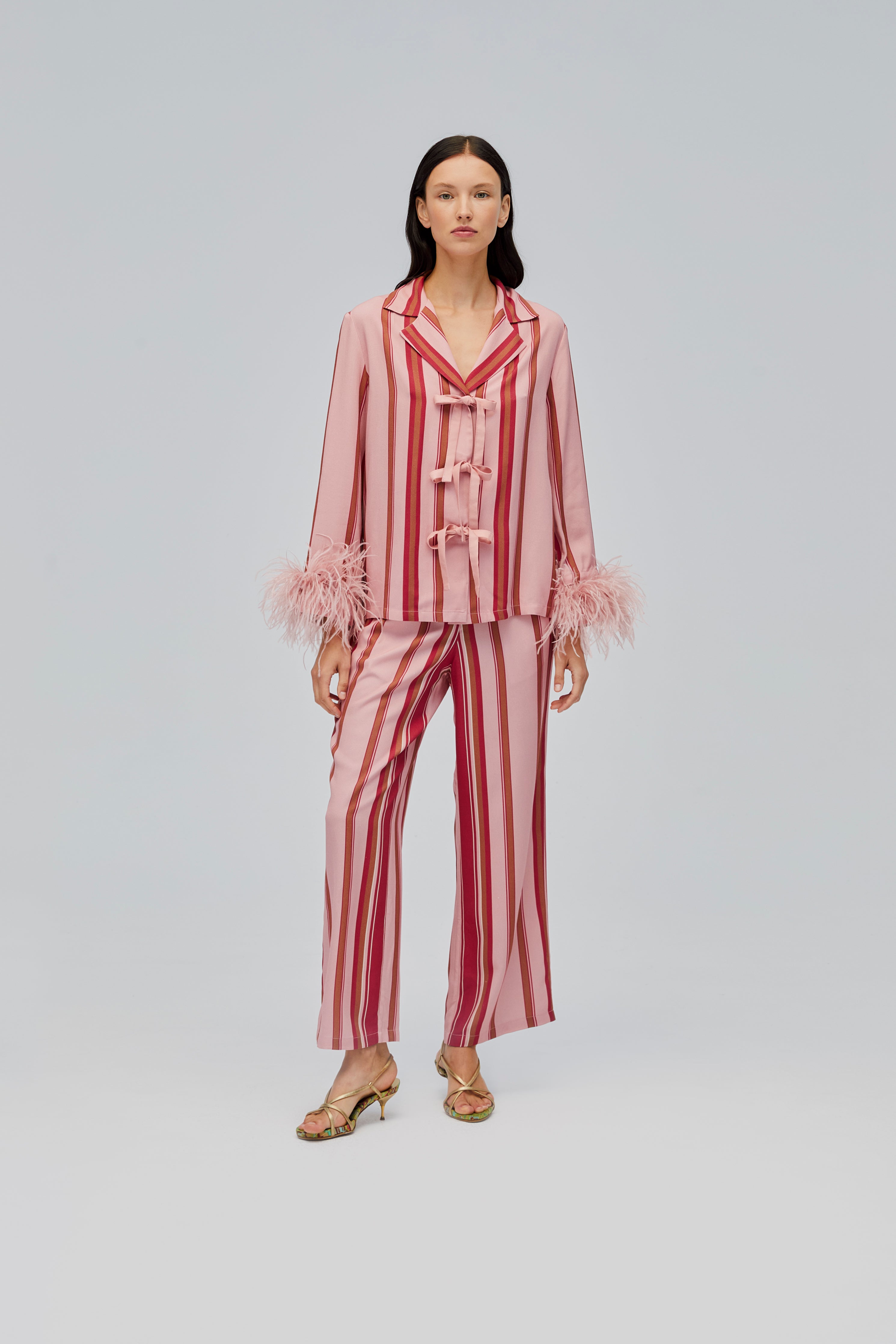 woman-wearing-red-and-pink-striped-long-sleeve-shirt-with-feather-cuffs-and-tie-bow-closures-long-pants