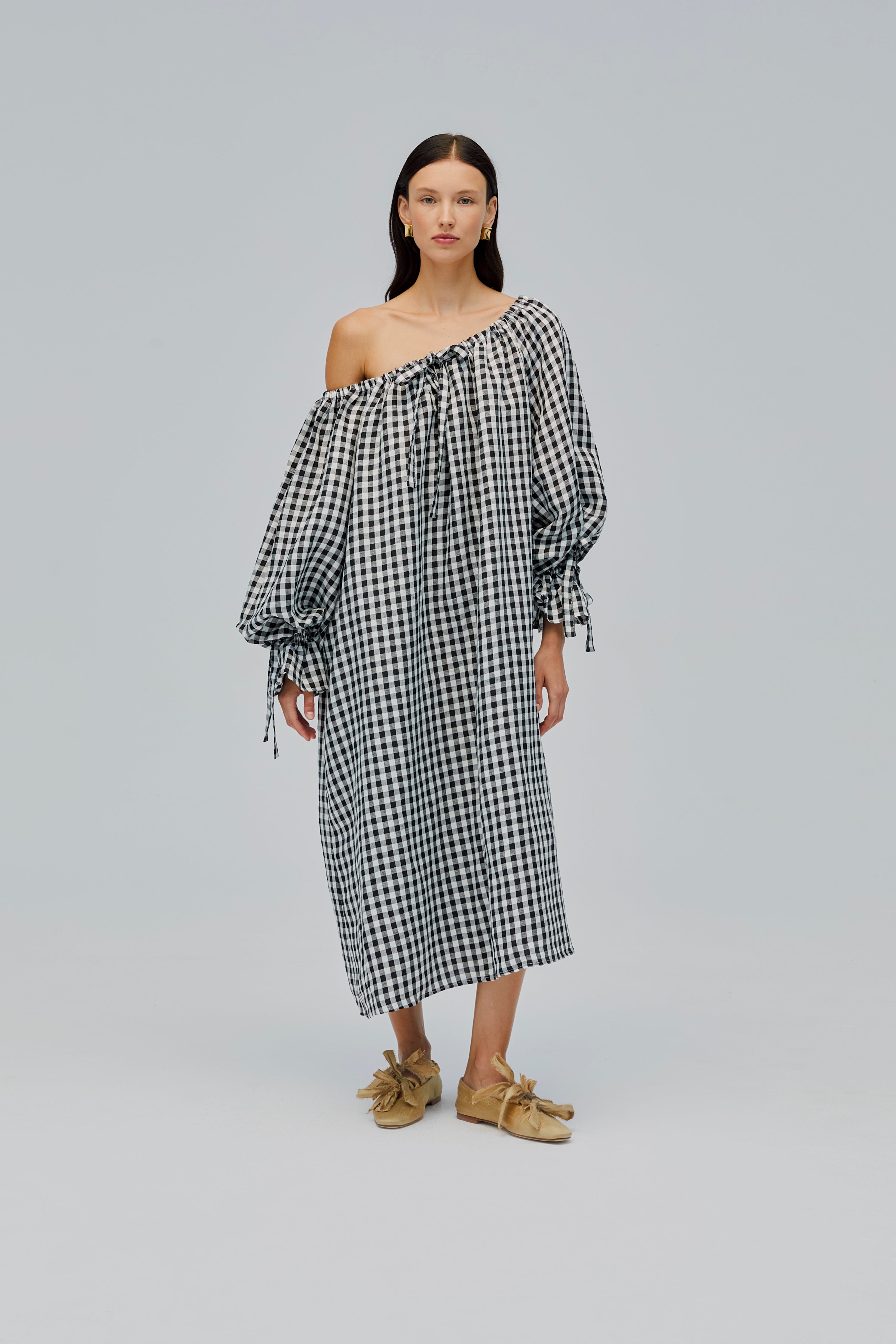 woman-wearing-black-gingham-dress-with-long-sleeves-tie-at-neckline-and-long-sleeve-cuffs-with-neckline-worn-off-the-shoulder-front