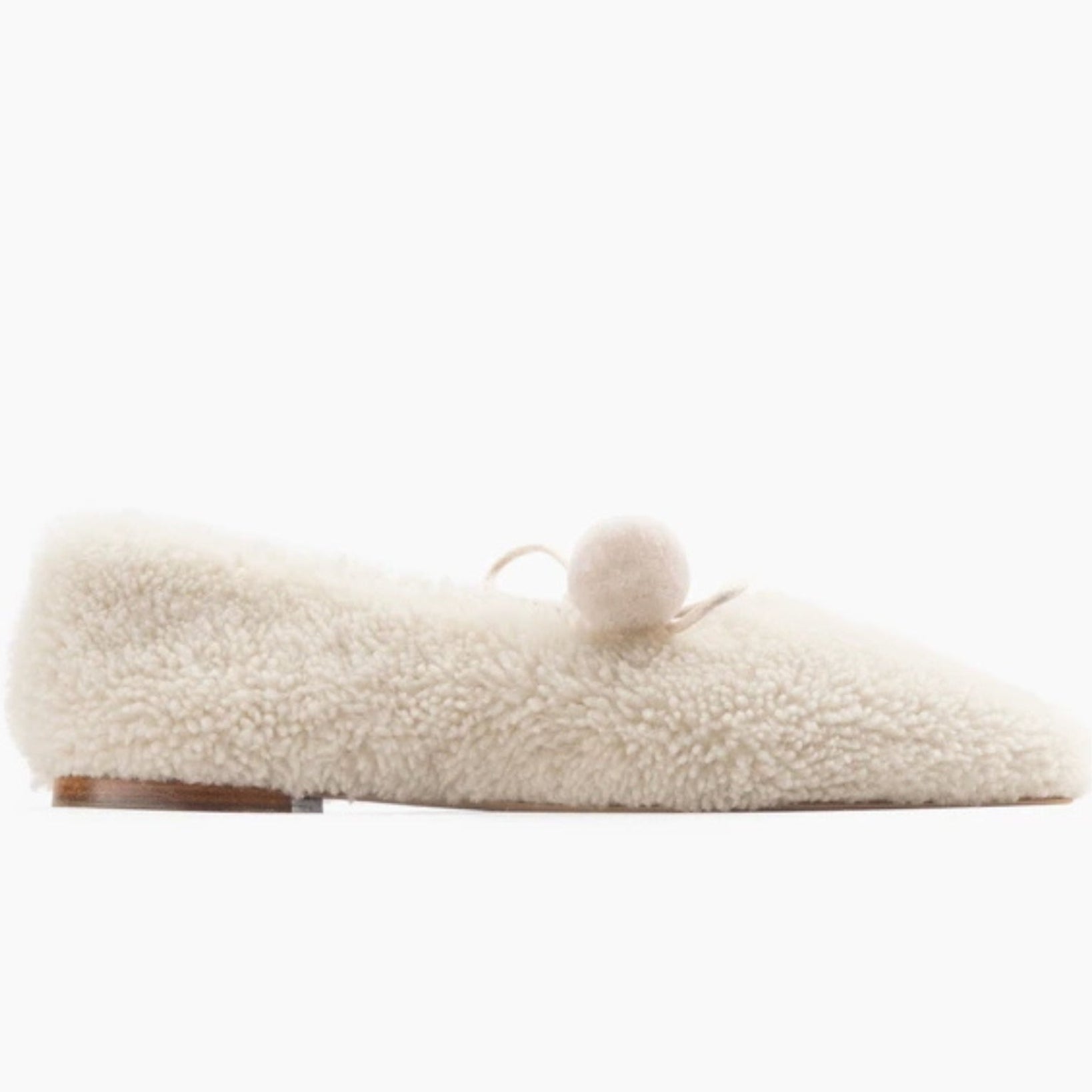 White shearling fluffy slippers with a pom-pom tie.