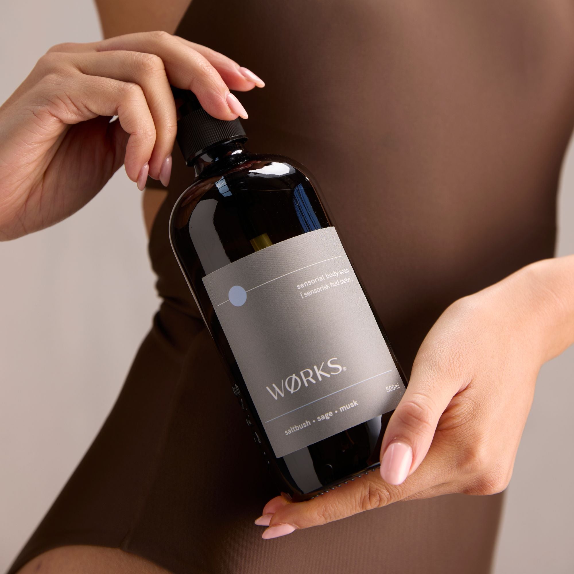 Person holding a brown pump glass bottle labelled 'Wörks'.