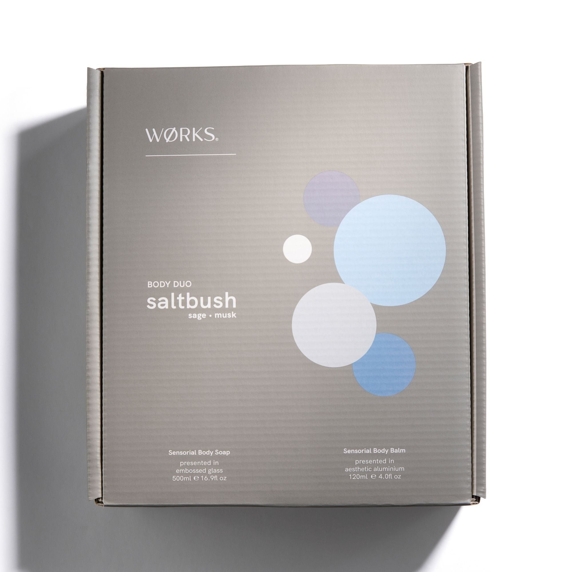 'Works' brand and saltbush body duo  text on grey box packaging with blue circles.