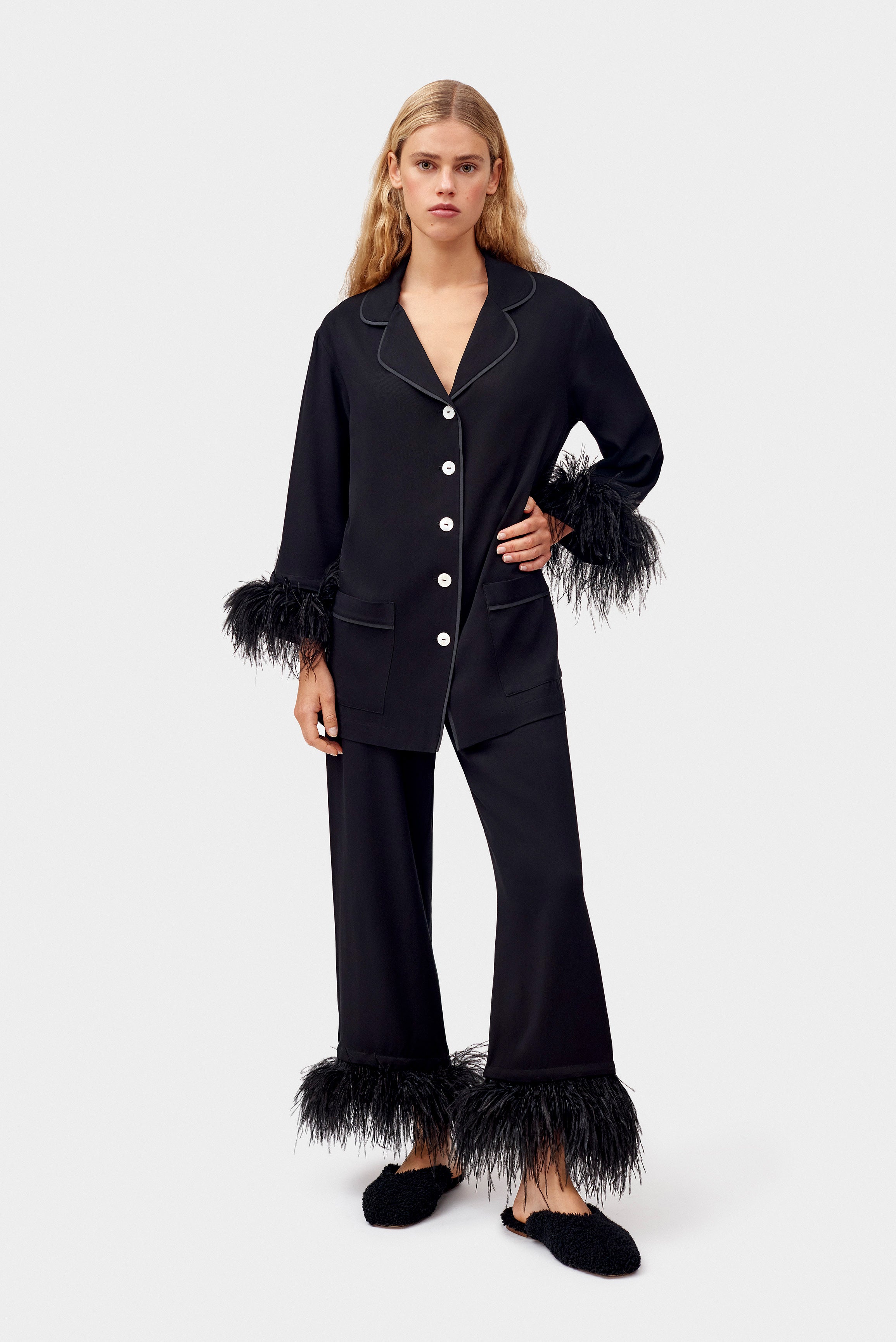 woman-standing-wearing-black-party-pyjamas-with-feather-cuffs-and-arm-on-hip