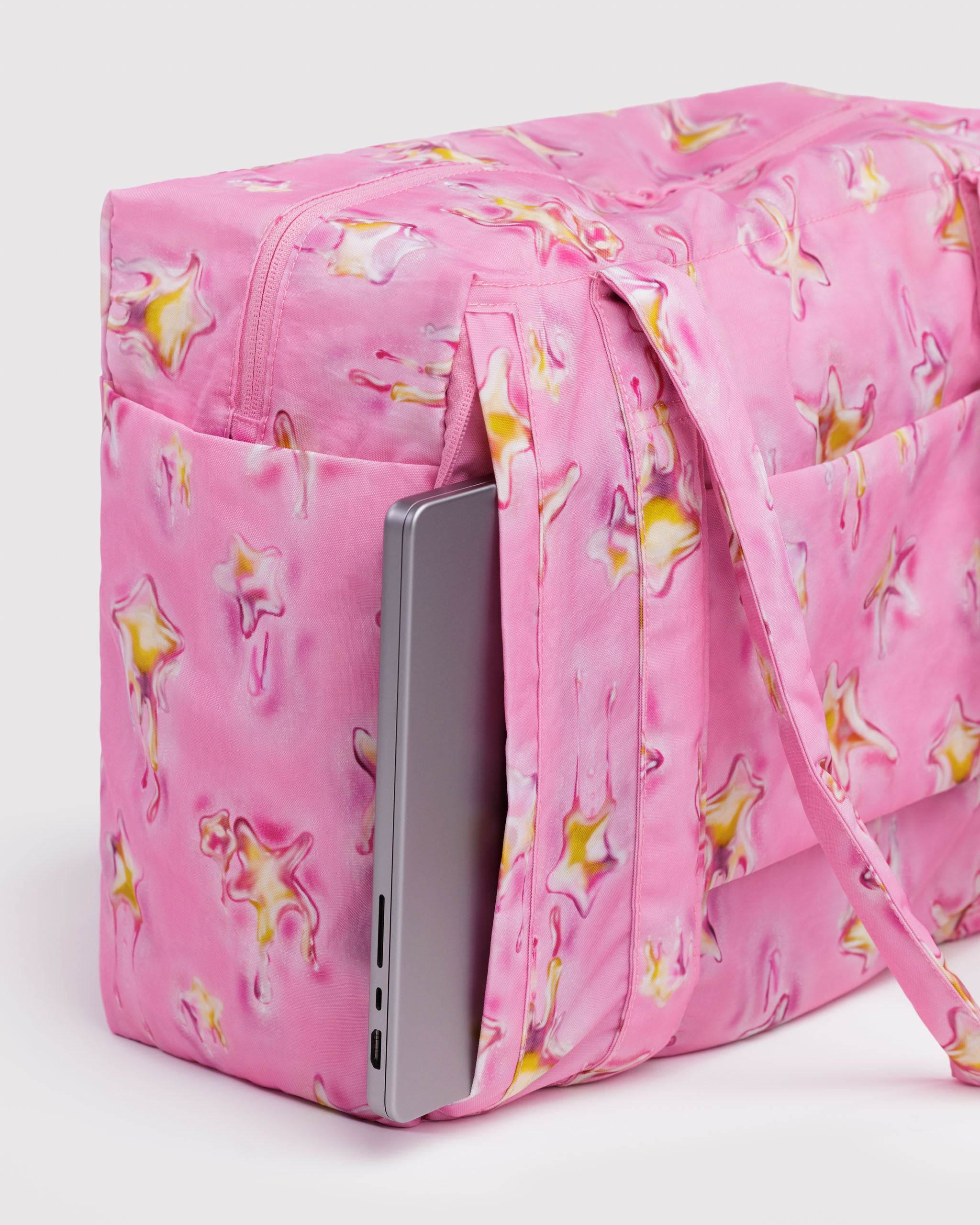 Pink star-patterned duffle bag with a laptop partially visible inside a side zip laptop compartment