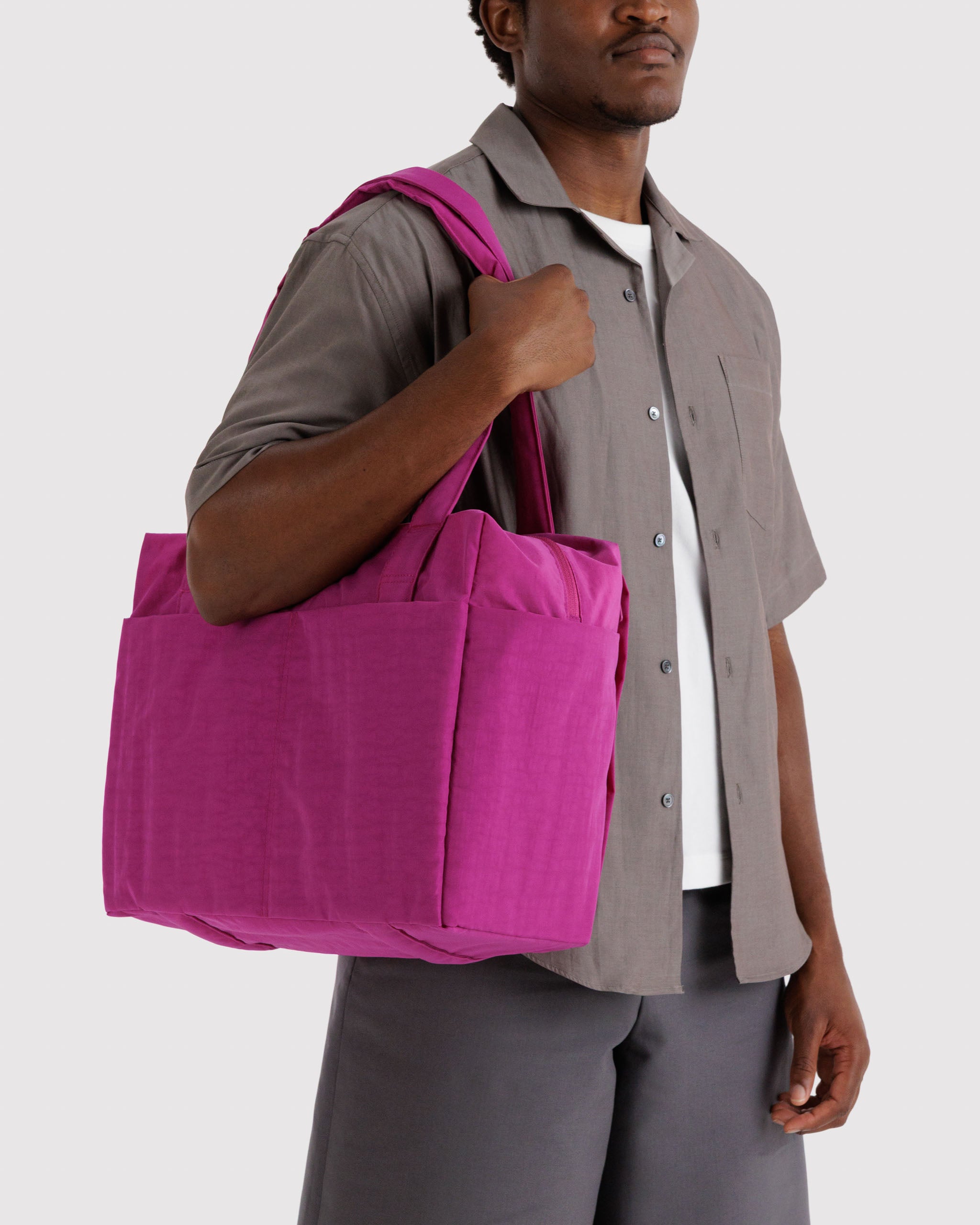 Man carrying a vibrant pink tote bag on shoulder.