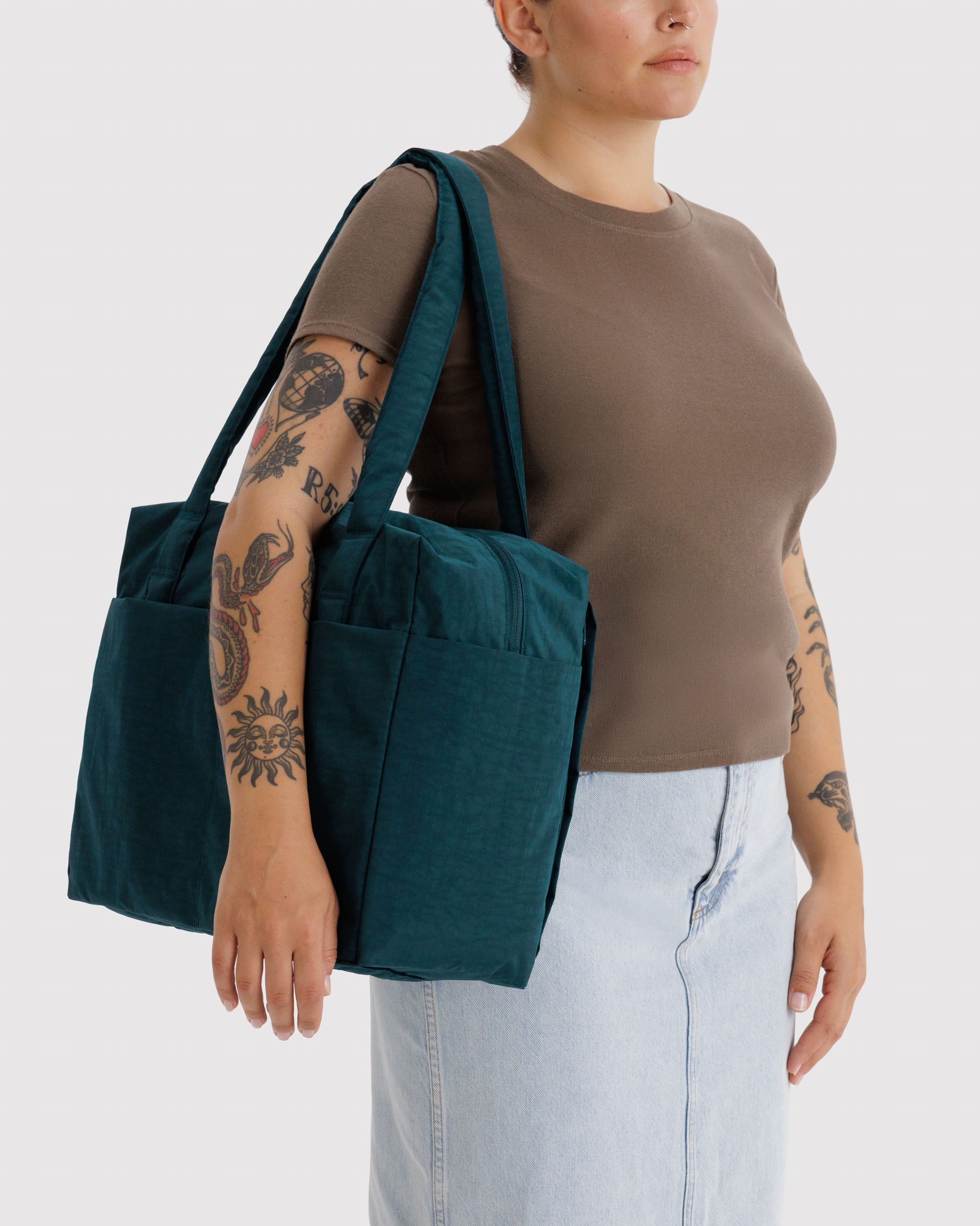 Person carrying a teal tote bag with double straps on shoulder.