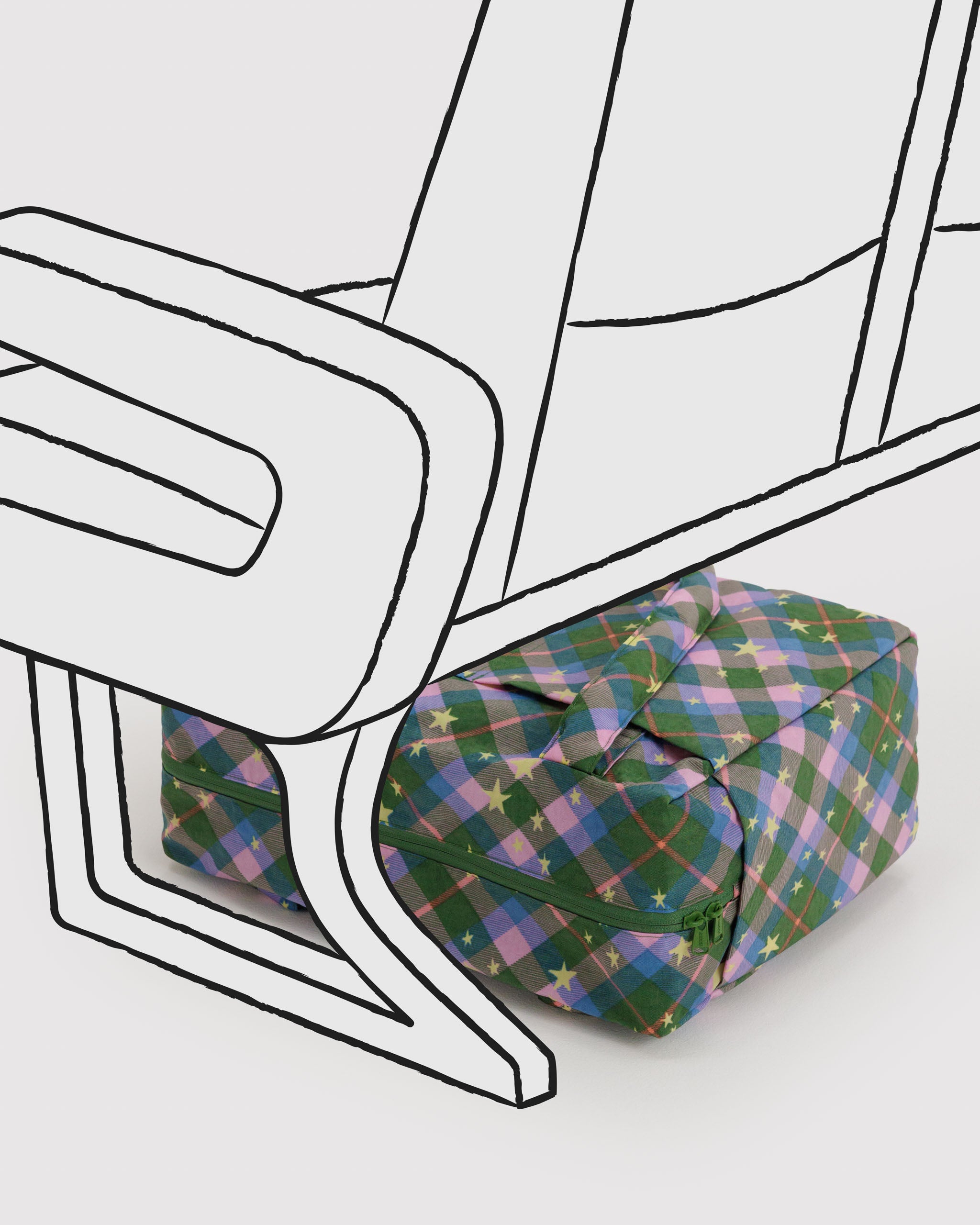 Green plaid tote bag with stars wit a closed top zip lying under an aircraft seat drawing.