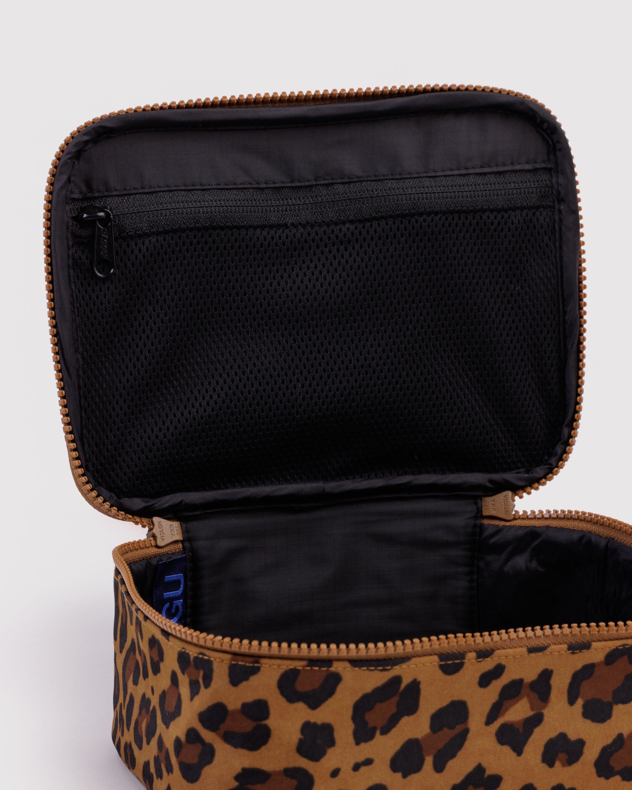 Leopard print cosmetic bag with black interior and zip mesh pocket inside lid.