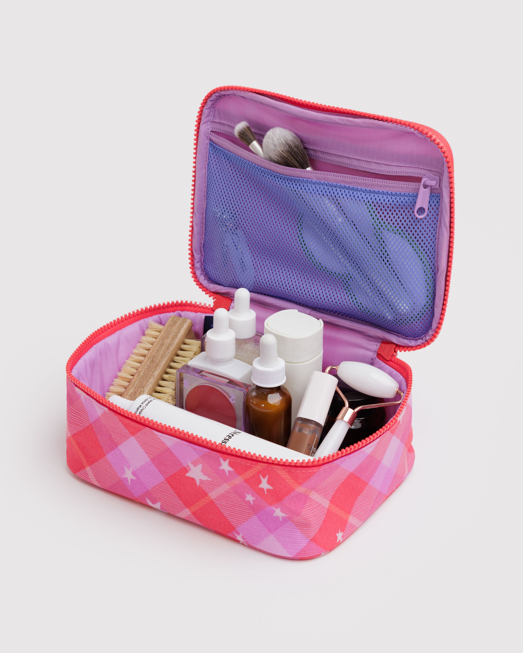 Pink plaid and stars print makeup bag with cosmetic items inside and in the zip mesh pouch on lid.