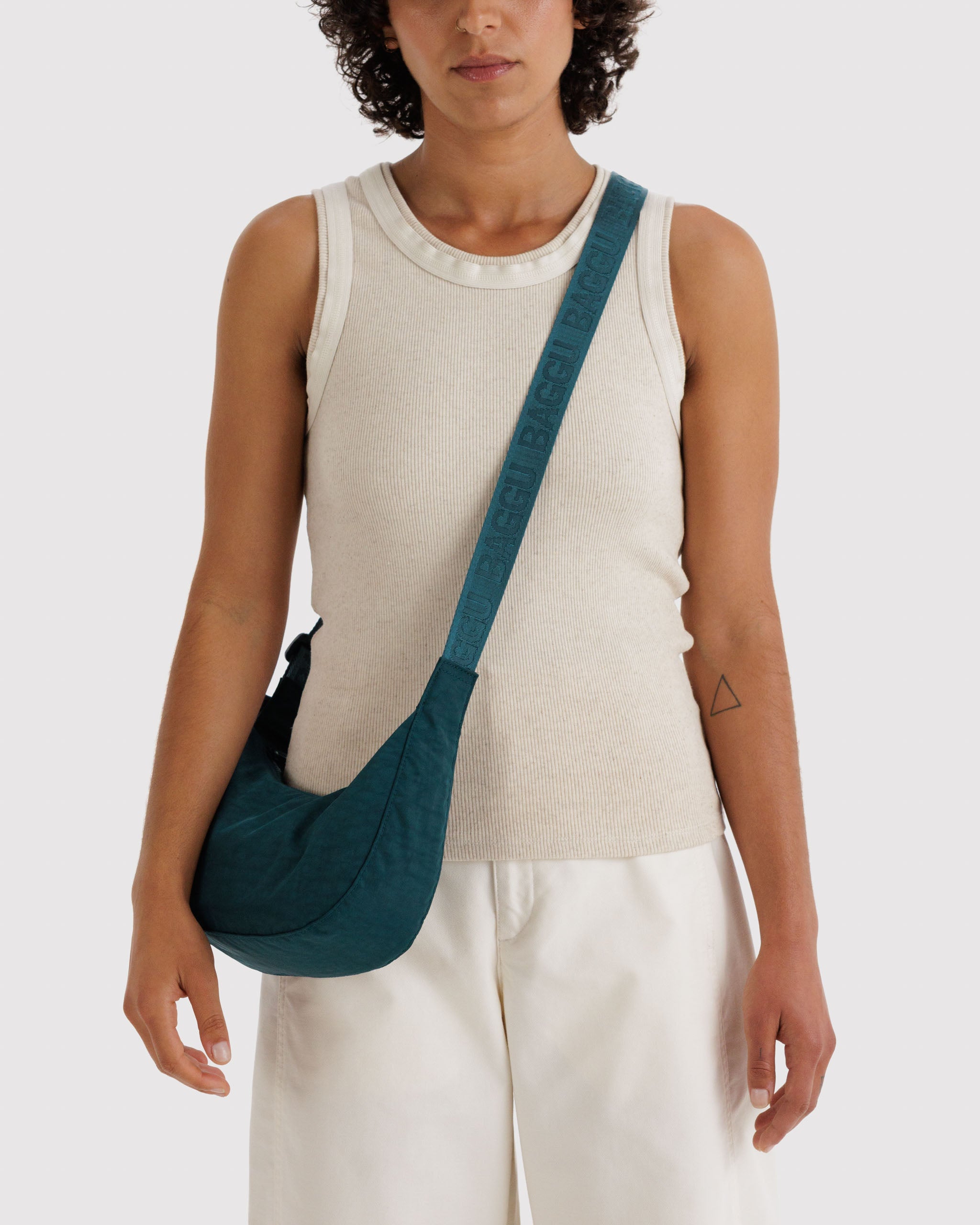 Woman wearing a teal crossbody bag with a wide adjustable strap.