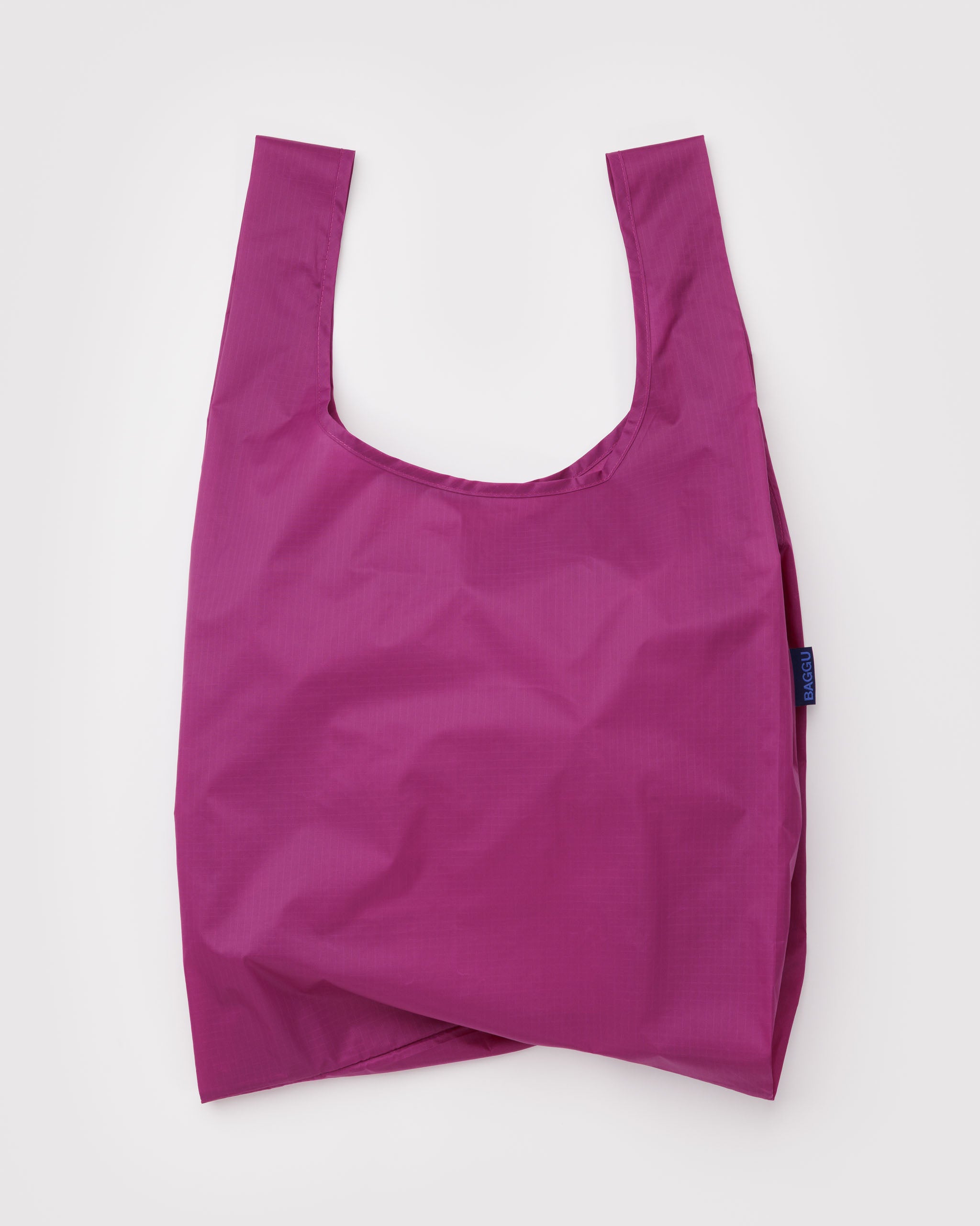 Vibrant pink reusable shopping tote bag with BAGGU logo tag at side.