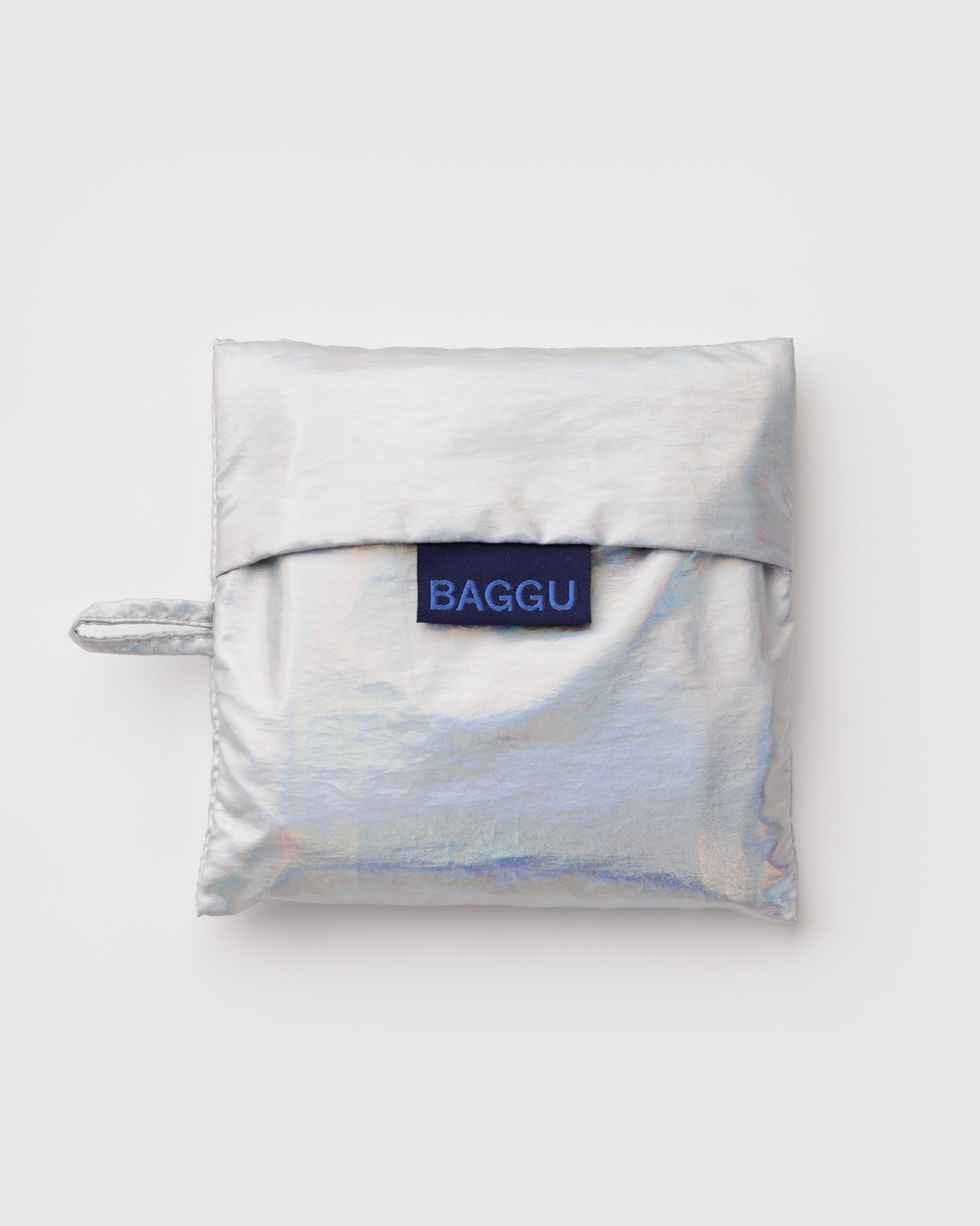 Metallic silver-grey folded fabric pouch with 'BAGGU' label and hanging loop with standard baggu inside.