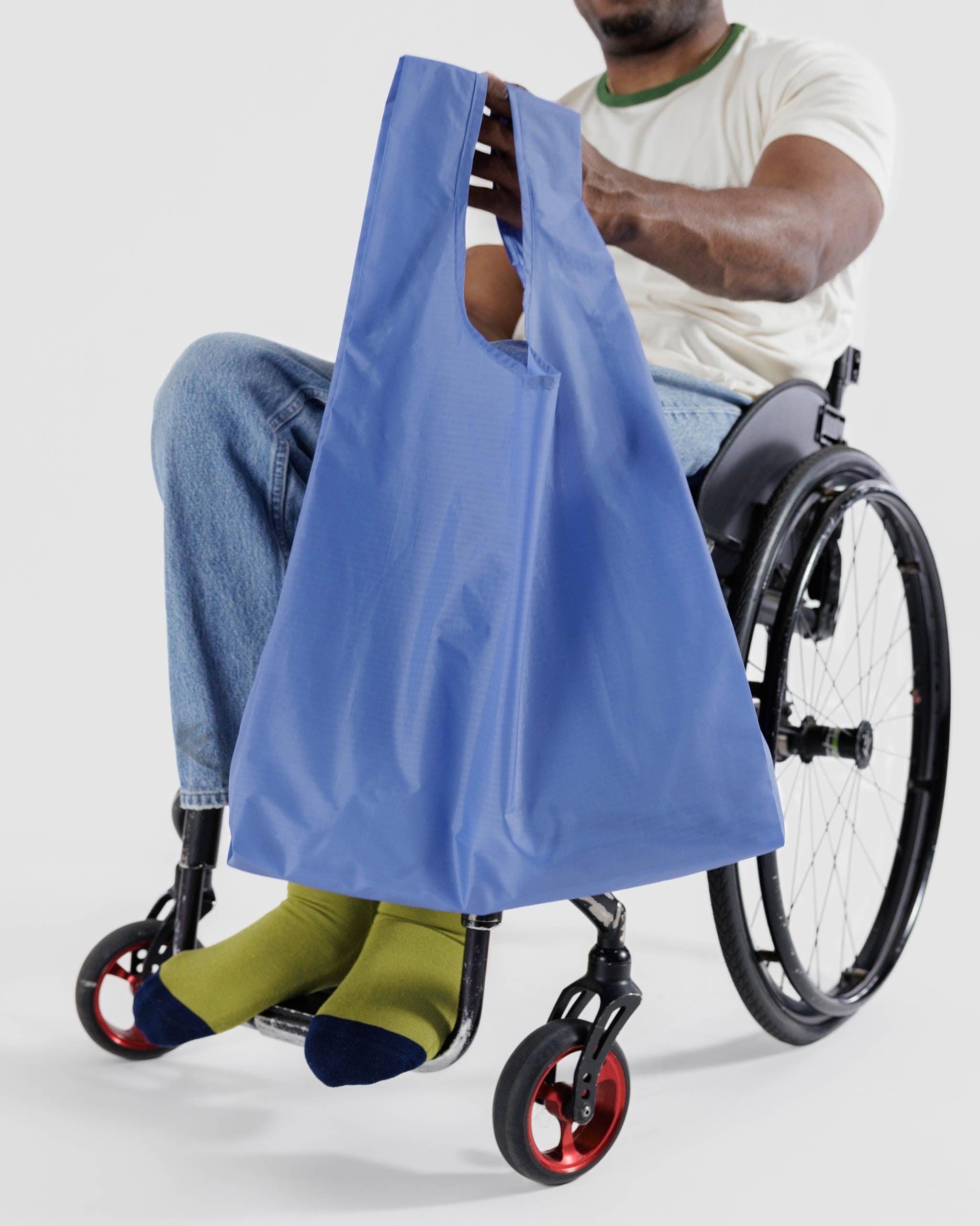 Baggu-standard-reusable-bag-in-pansy-blue-being-held-by-a-man-in-wheelchair