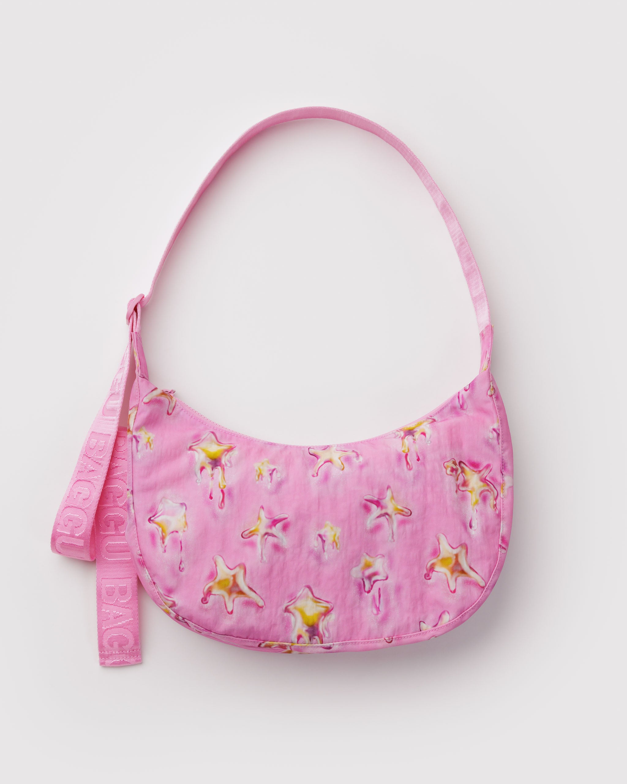 Pink medium crescent crossbody bag with yellow melting stars print with webbed adjustable strap and tonal top zipper