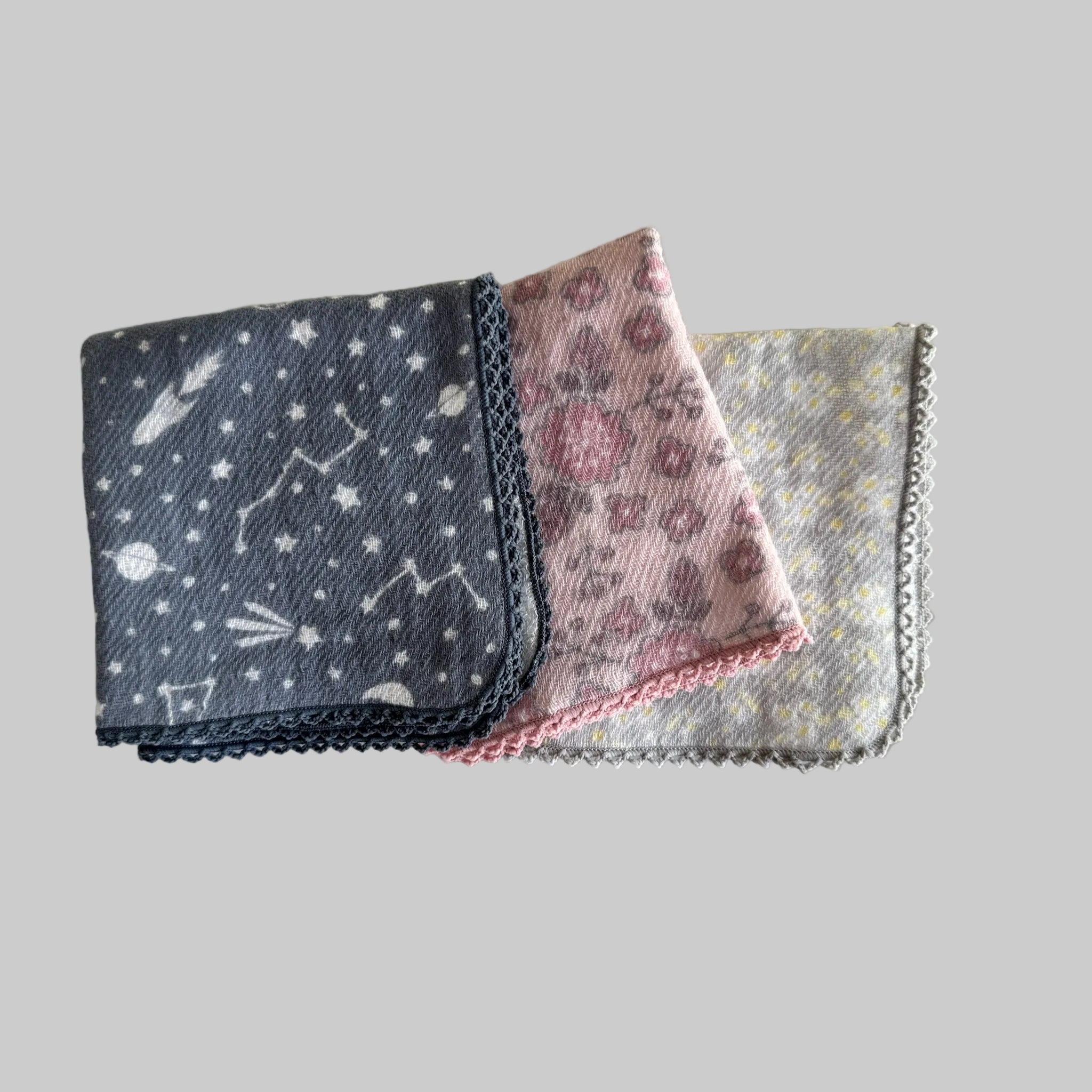 Stack of folded face cloths with delicate crotchet edge in various colours.
