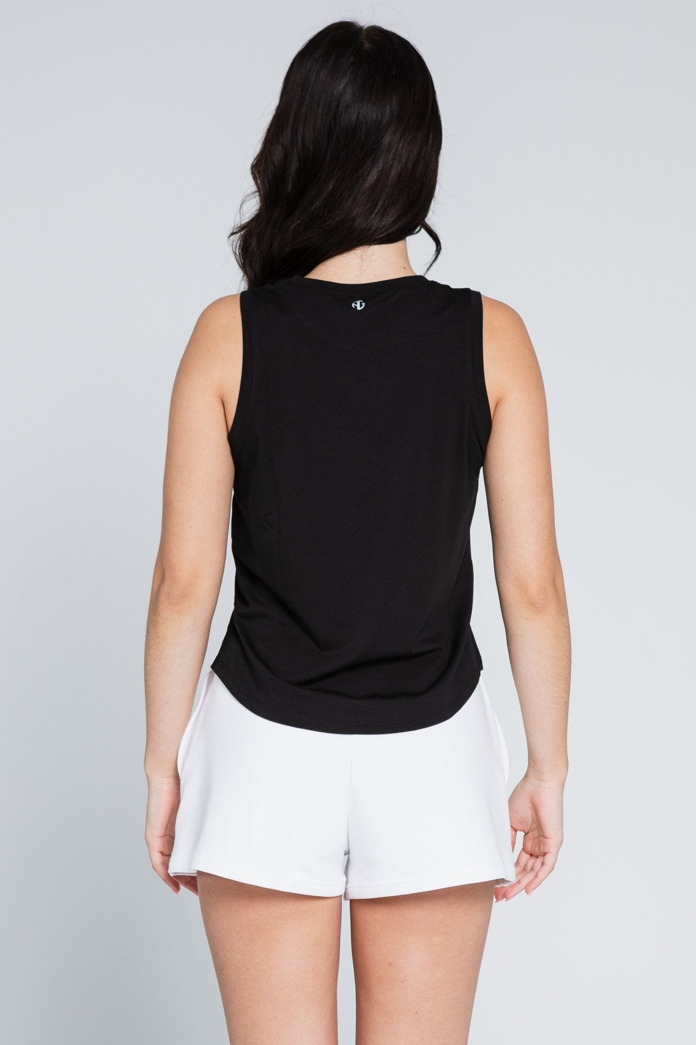 Back of a woman wearing a black tank and white sweat shorts.