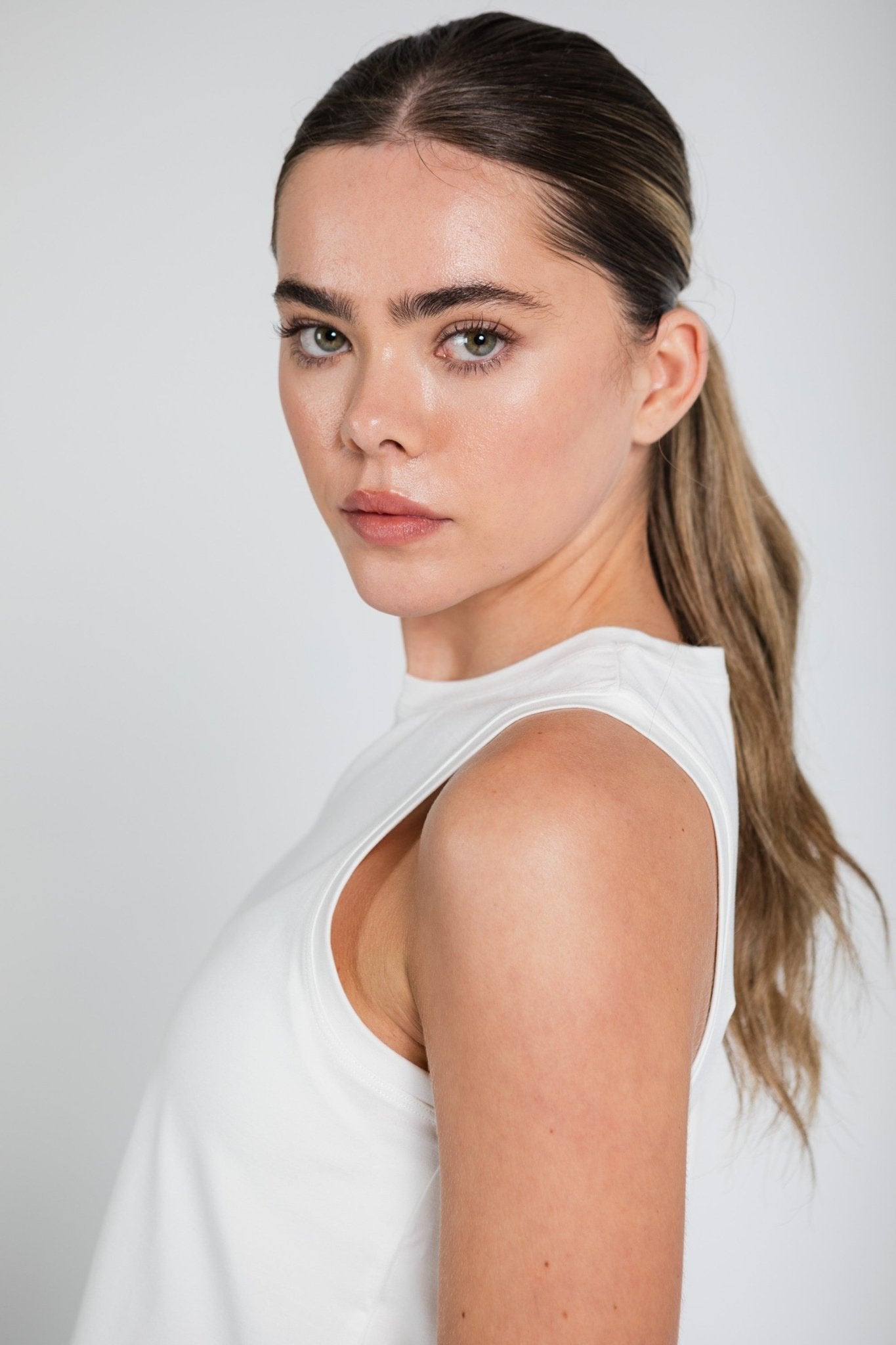 Close up of side armhole of white tank top worn by a woman.