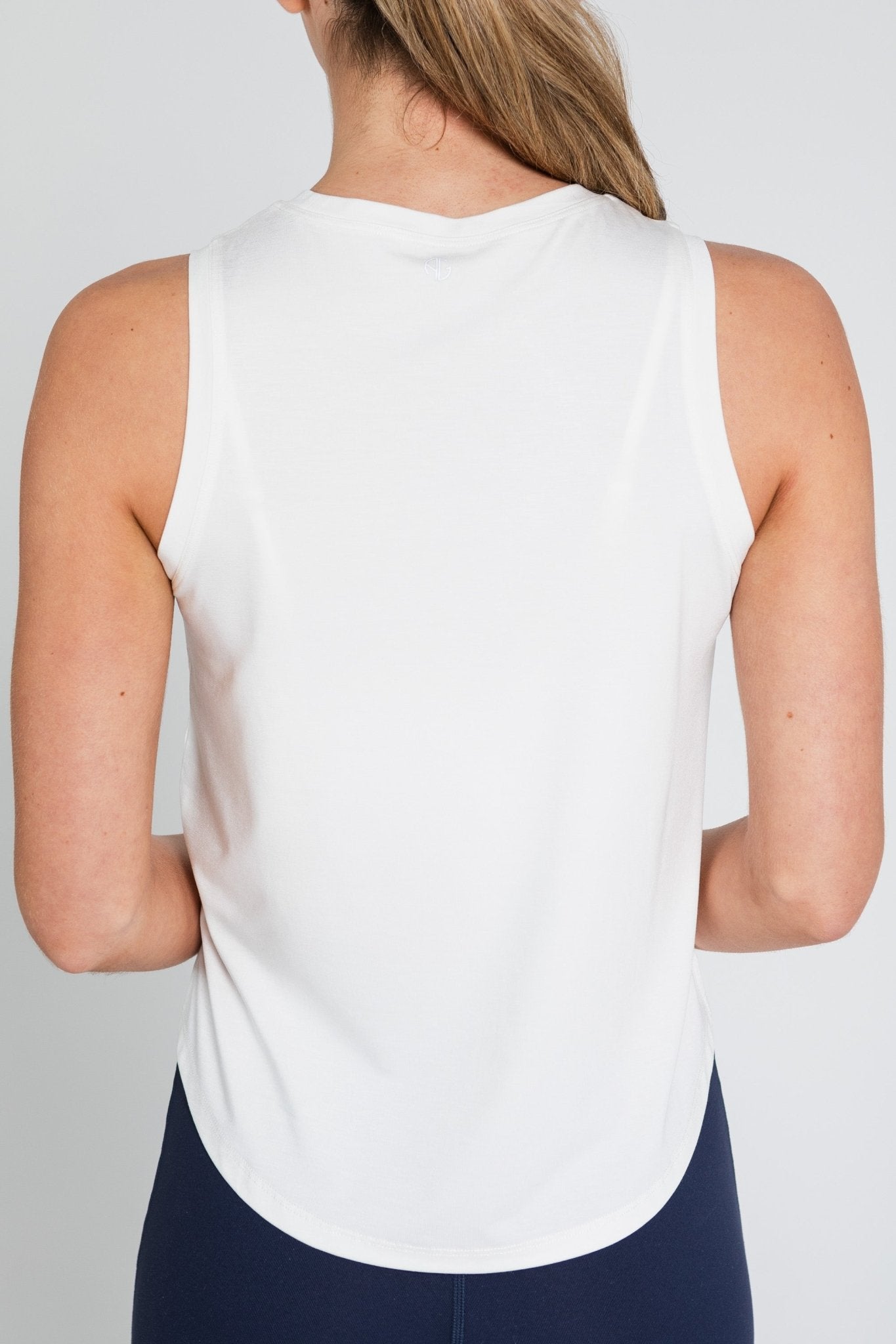 Back of a woman wearing a white tank top.