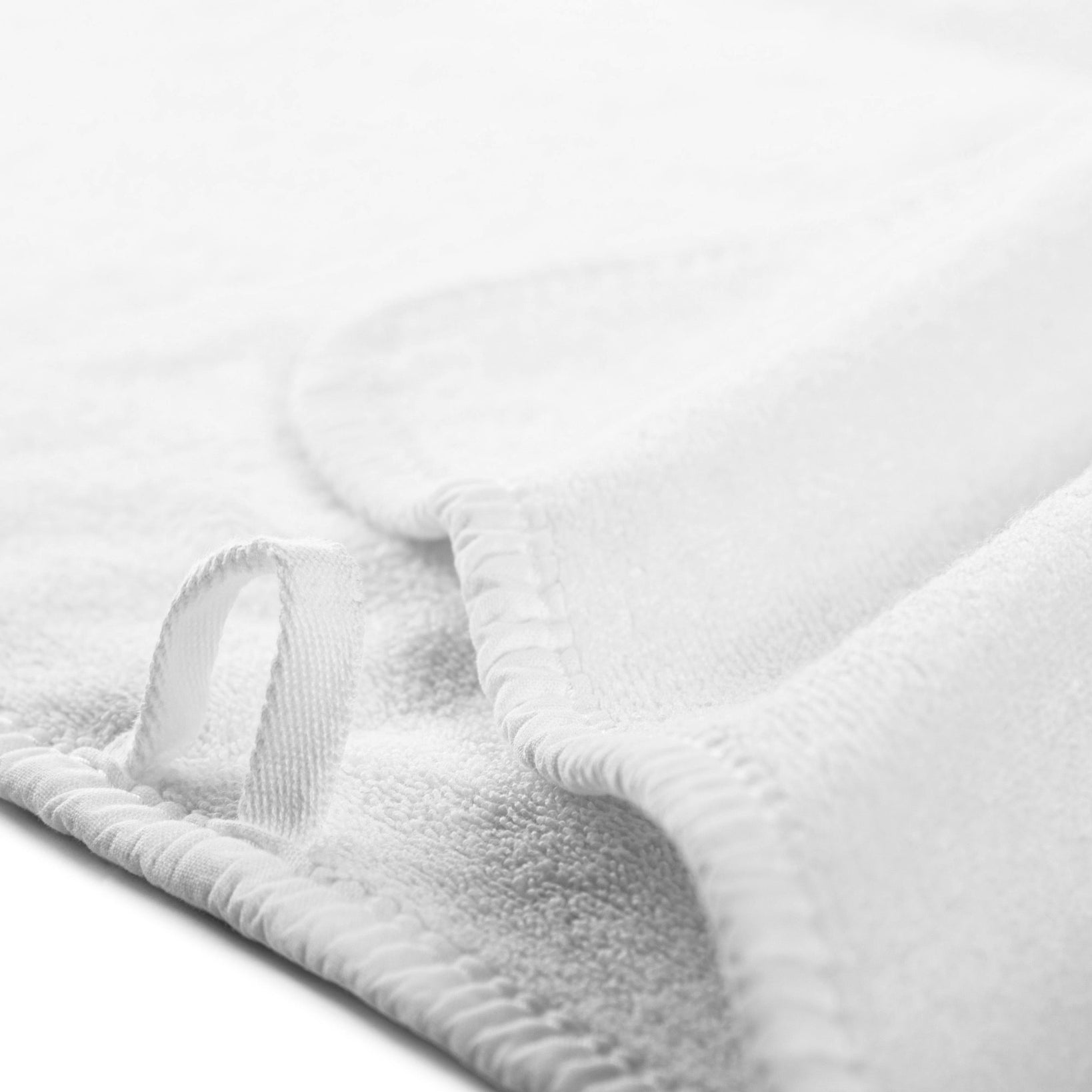Close up of white sports towel with hanging loop and edged in white bias binding. 