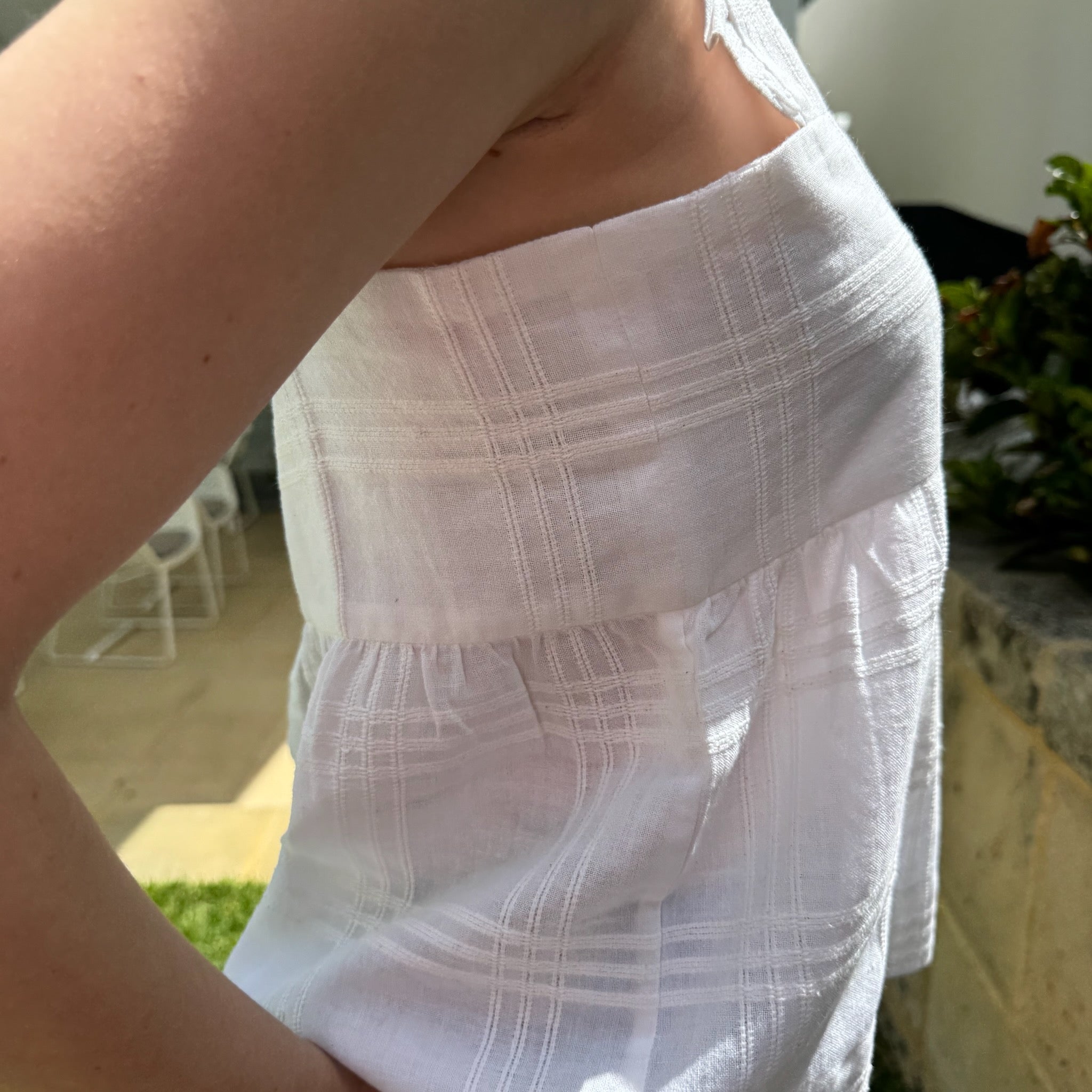 Side of woman wearing white cami top