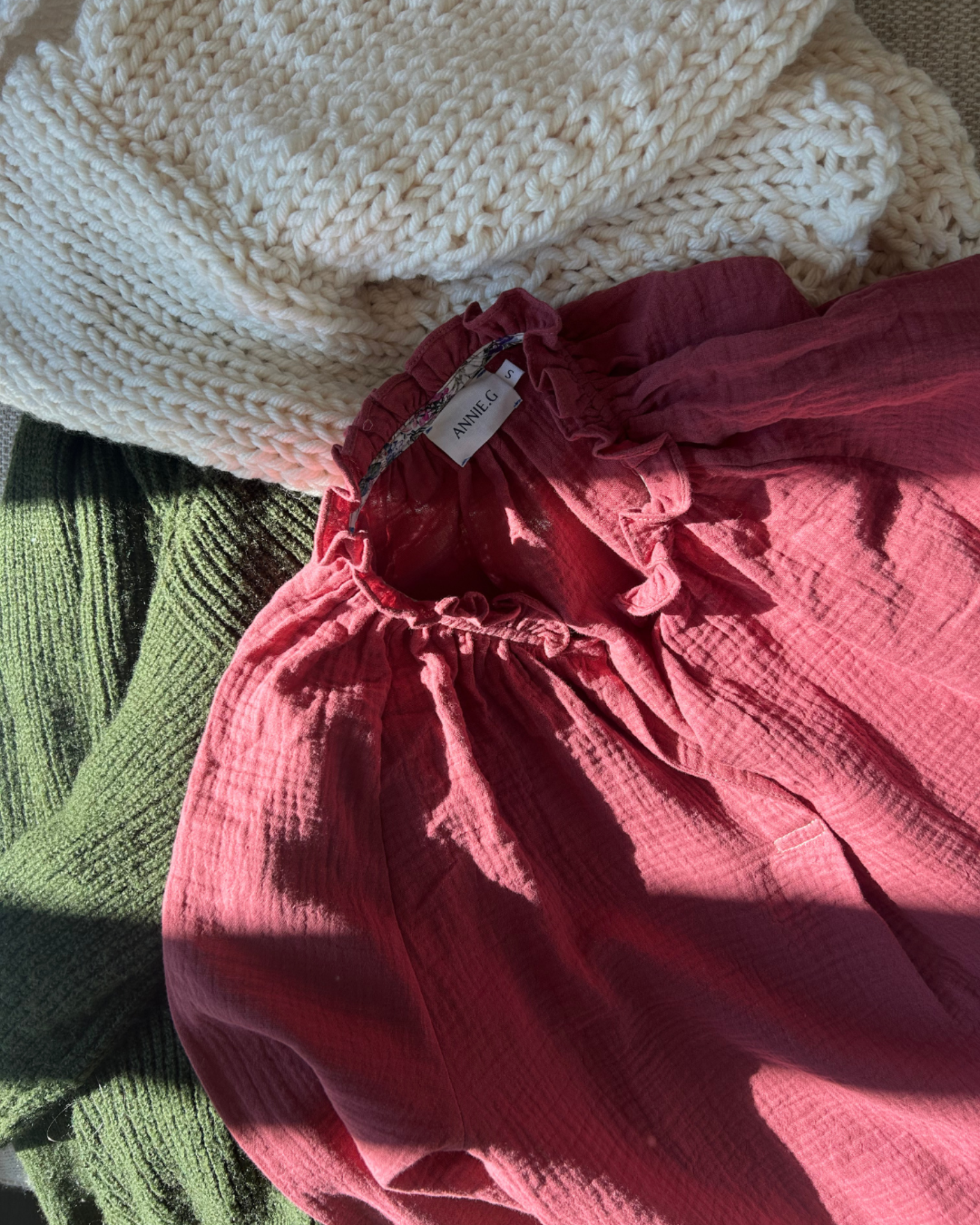 Close-up of a maroon cotton gauze top on stack of clothes.