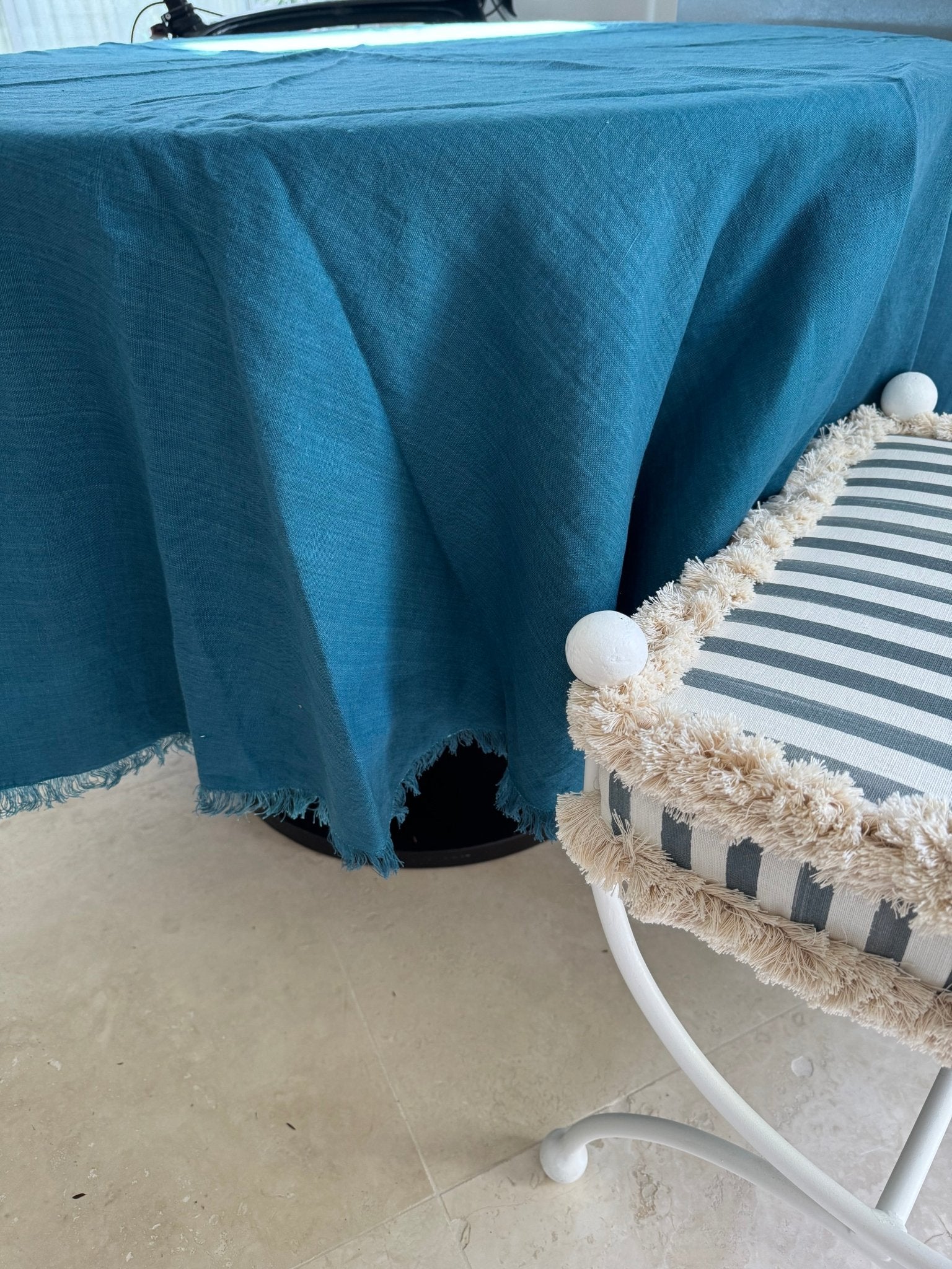 Round ocean blue tablecloth with fringe edge on a round table and a stool