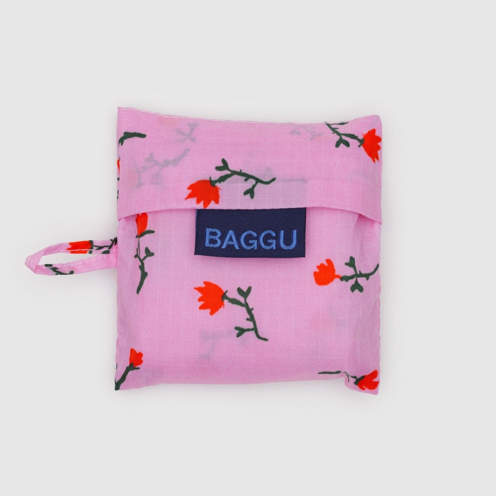 Baby Baggu reusable bag storage pouch in pink with red wildflower pattern, 'BAGGU' logo tag and keychain loop on the side