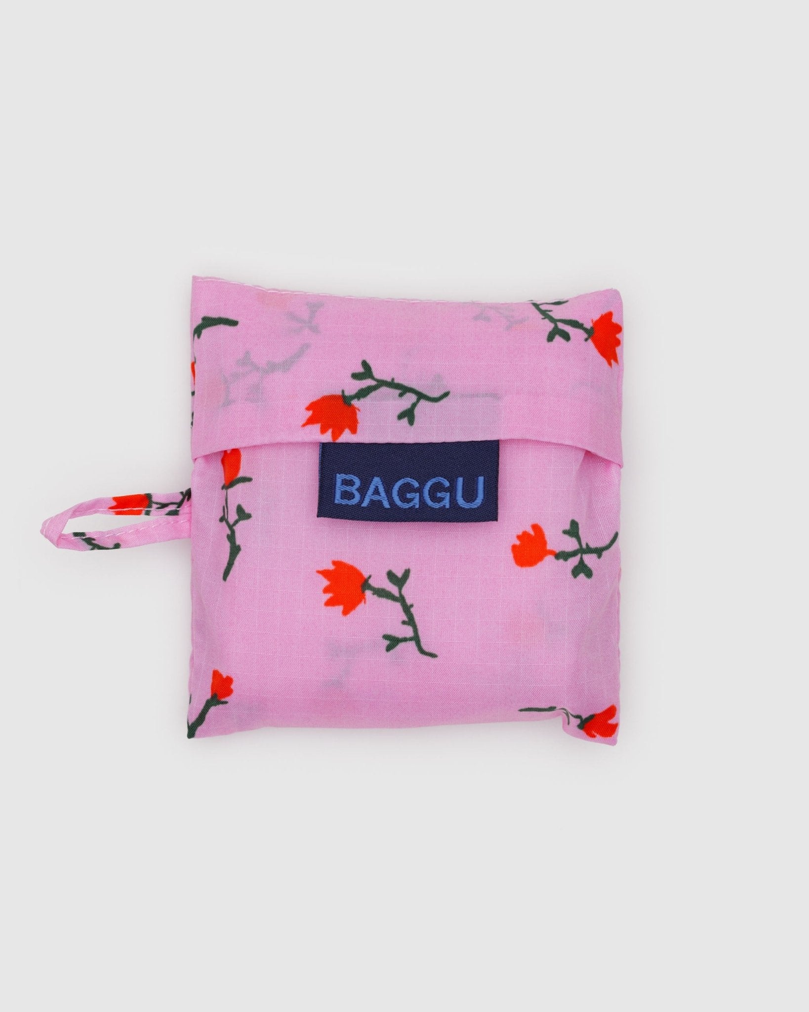Baby Baggu reusable bag storage pouch in pink with red wildflower pattern, 'BAGGU' logo tag and keychain loop on the side
