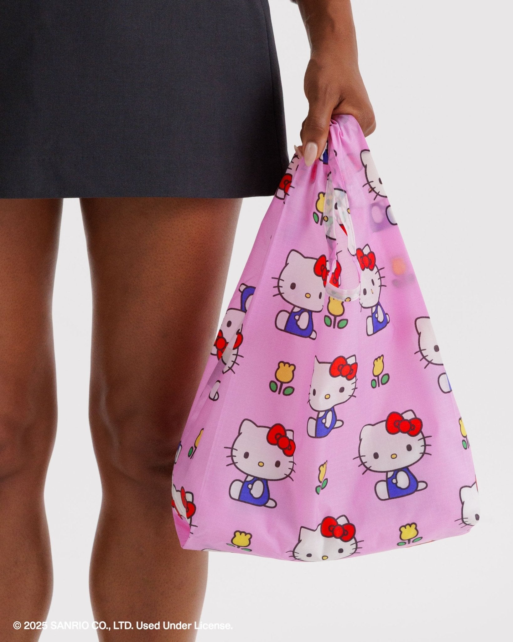 Person holding a pink Hello Kitty print baby size reusable bag 