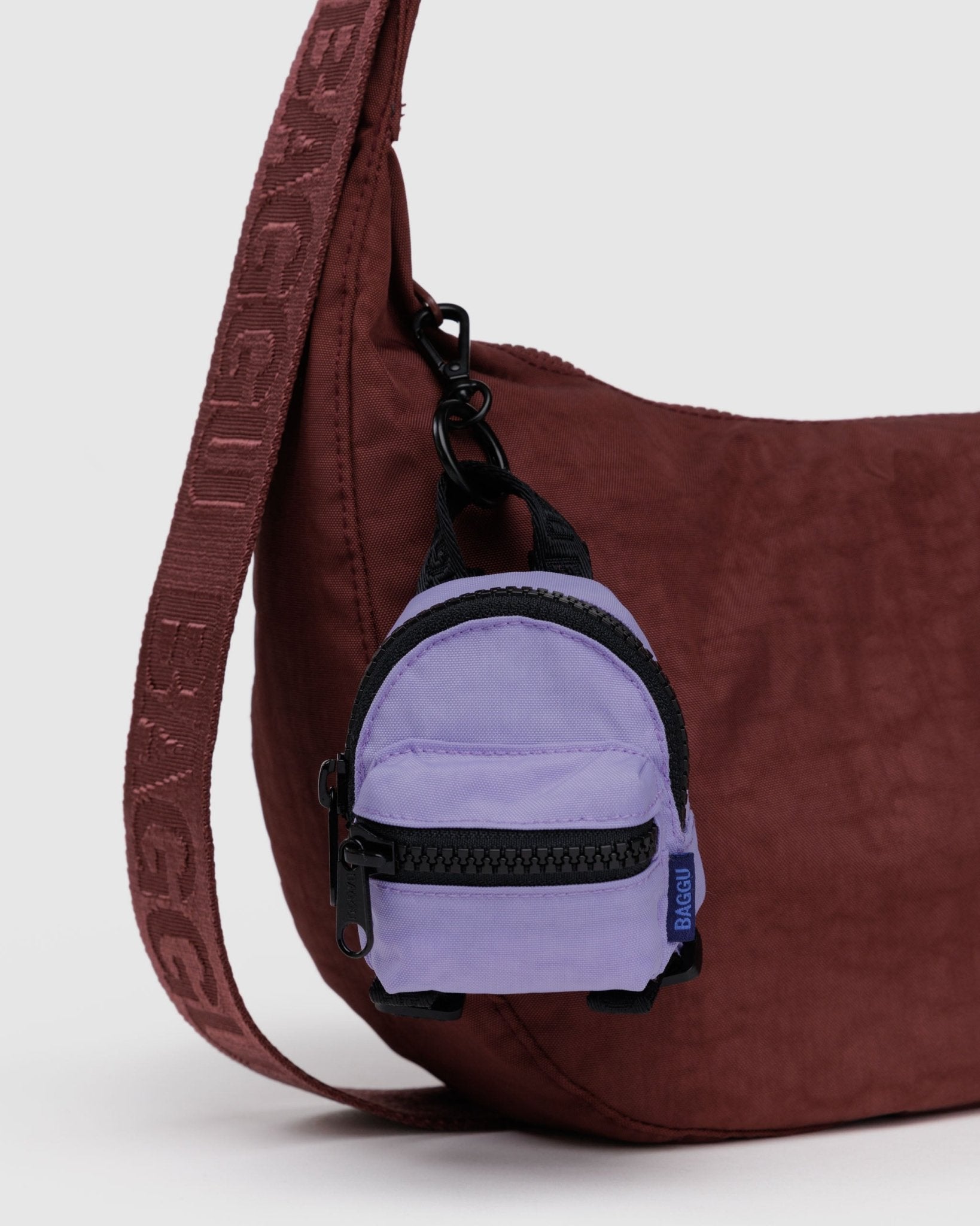 Purple backpack charm attached to a burgundy bag zipper
