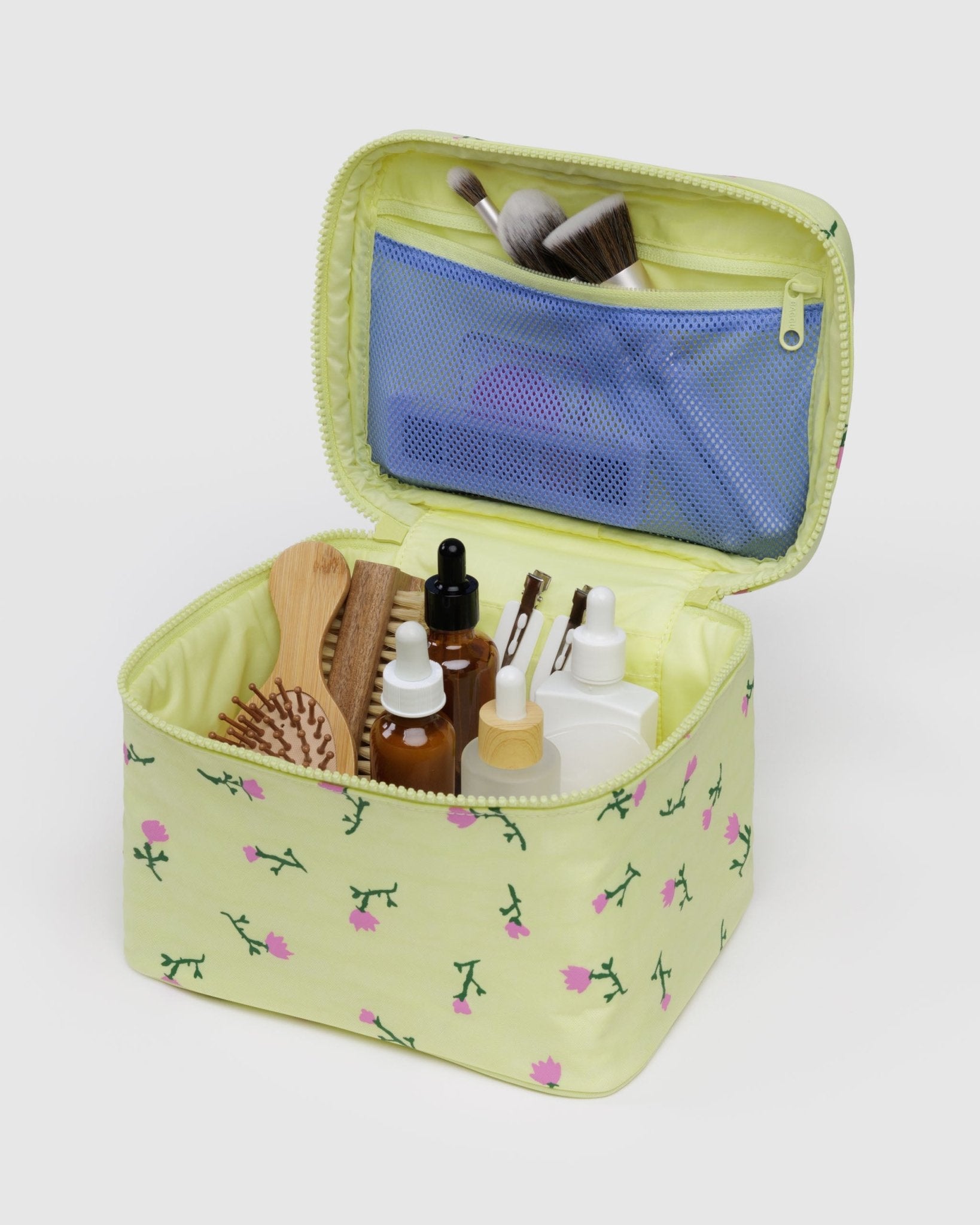 Large yellow cosmetic bag with wildflower floral pattern containing beauty products in main compartment and top zip pocket