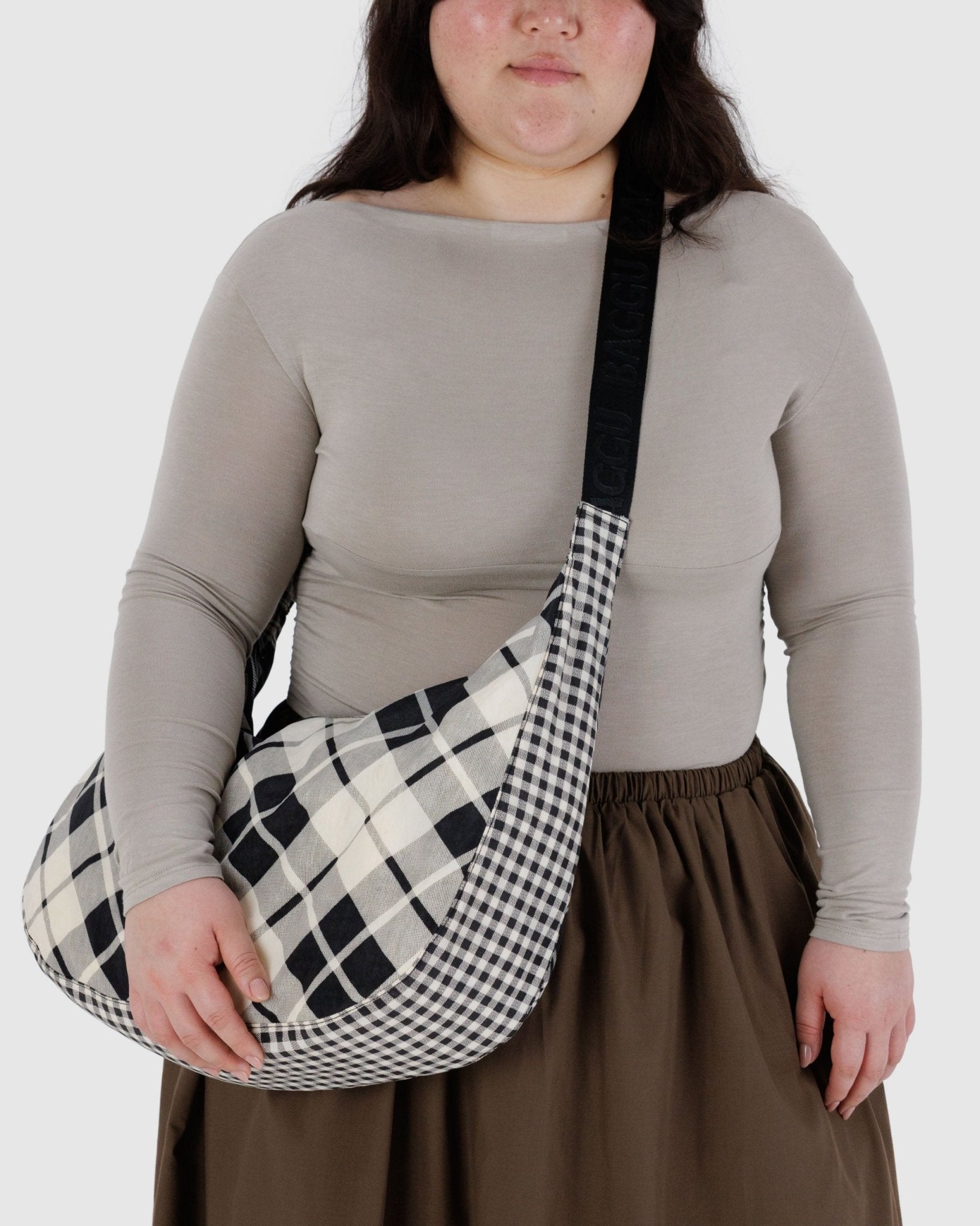 Person wearing a crossbody black and white plaid bag 