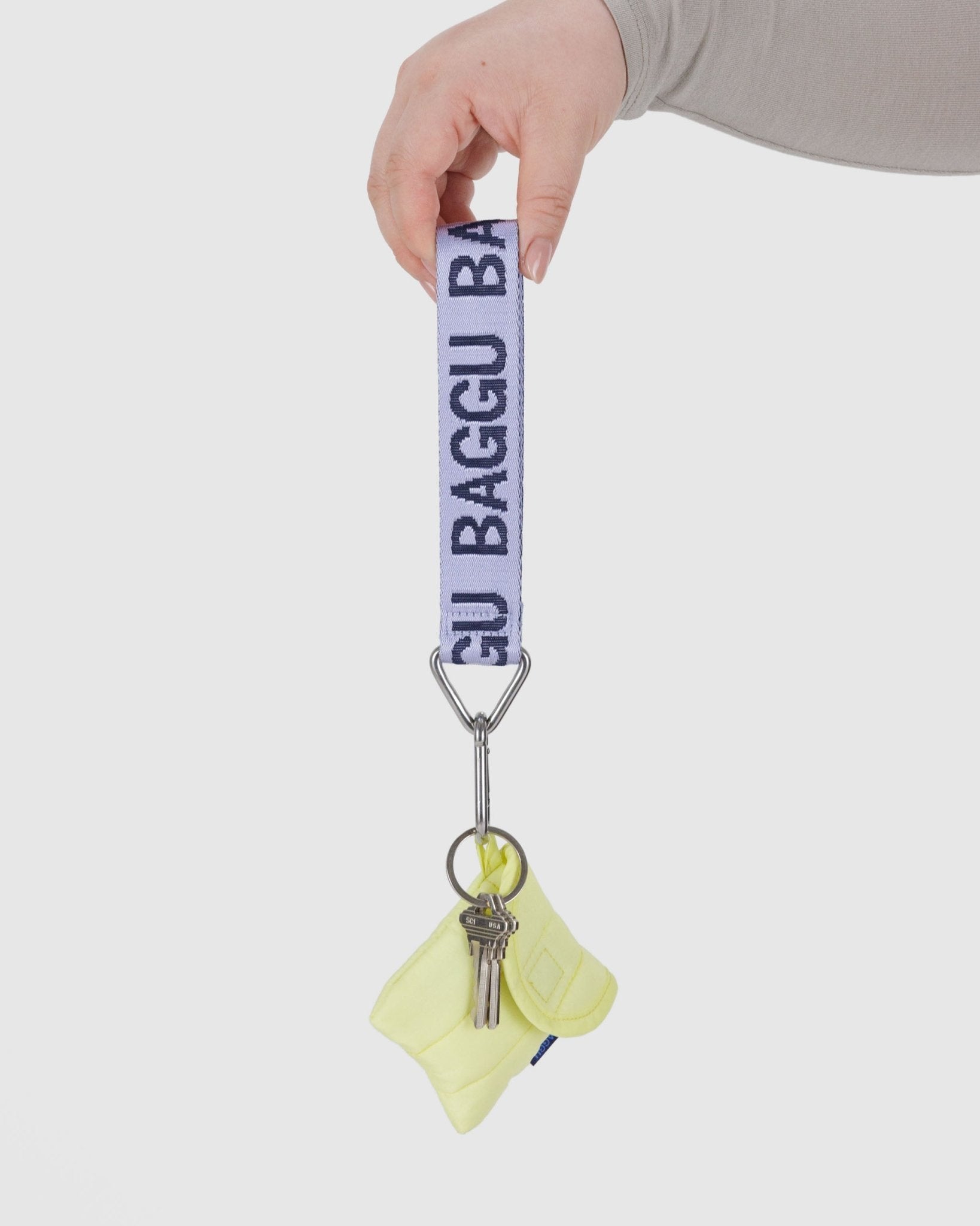 hand holding a Baggu Logo Keychain in dusty lilac with keys and earbuds case attached
