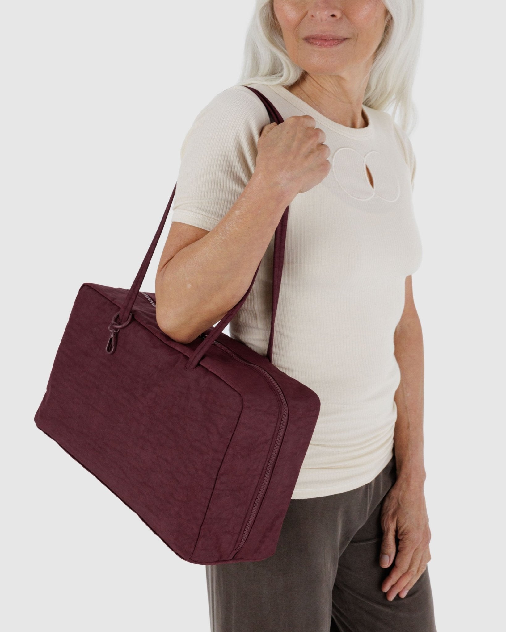 Woman holding a burgundy shoulder bag 