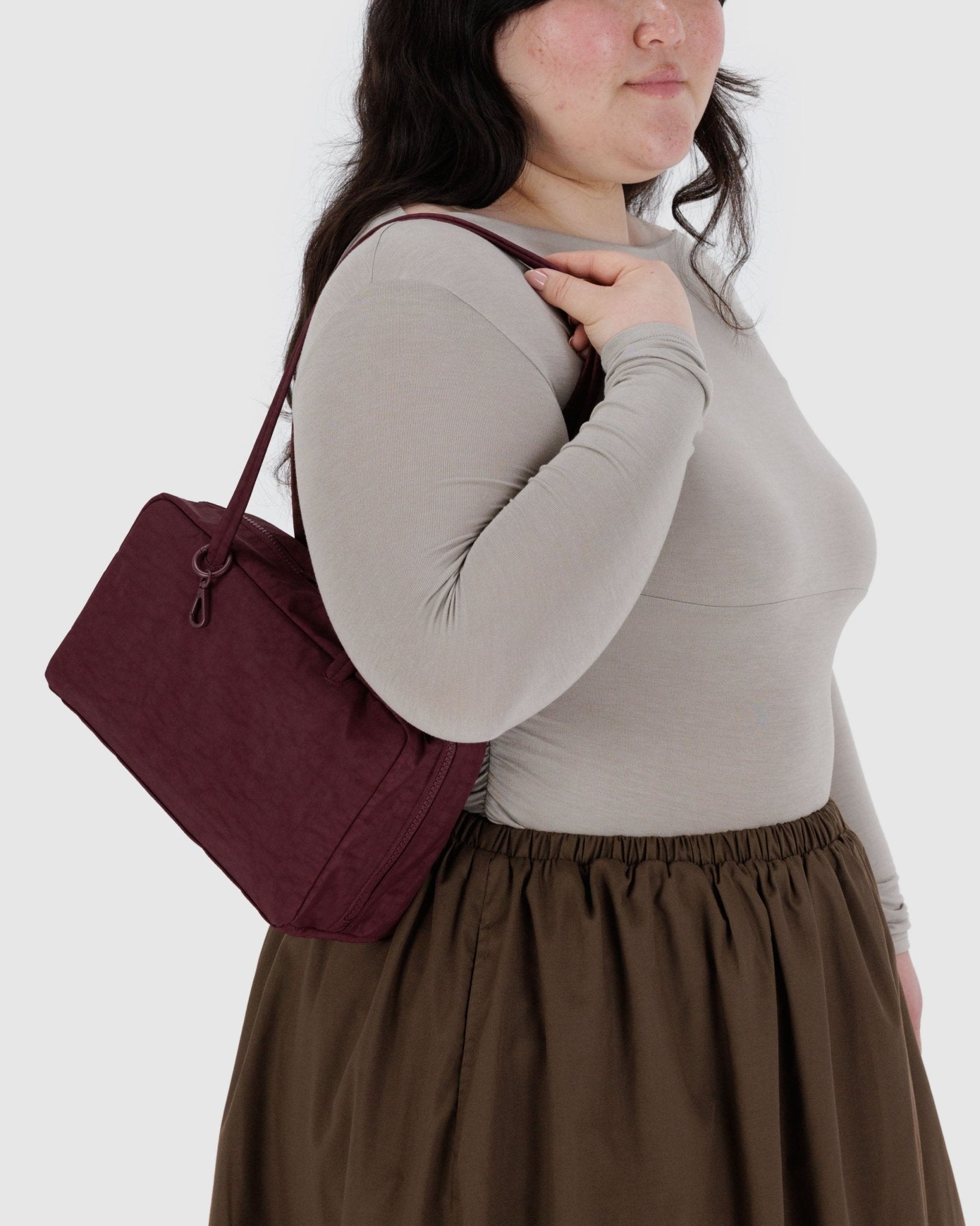 Woman holding a maroon handbag on shoulder