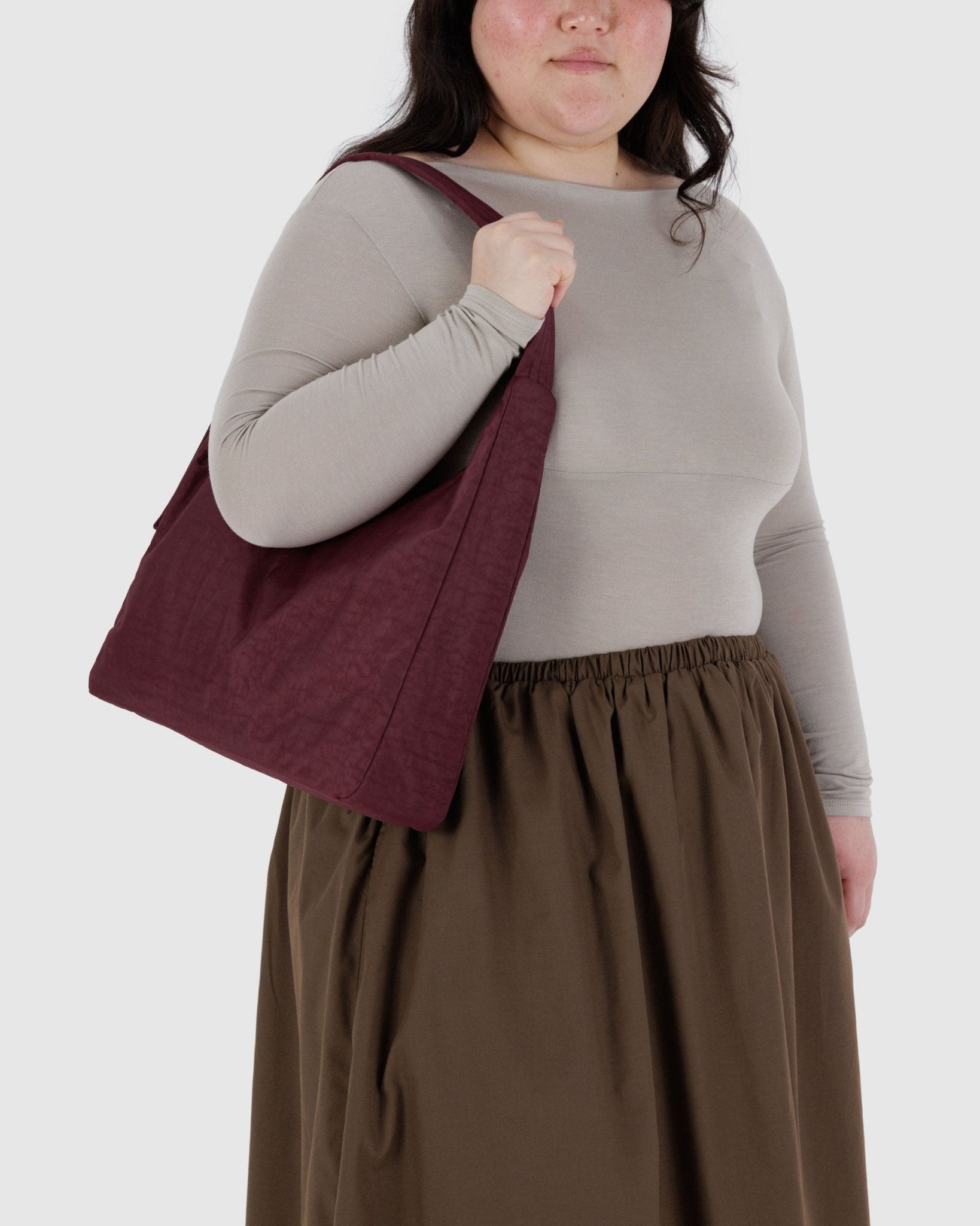 Person holding a maroon tote bag 