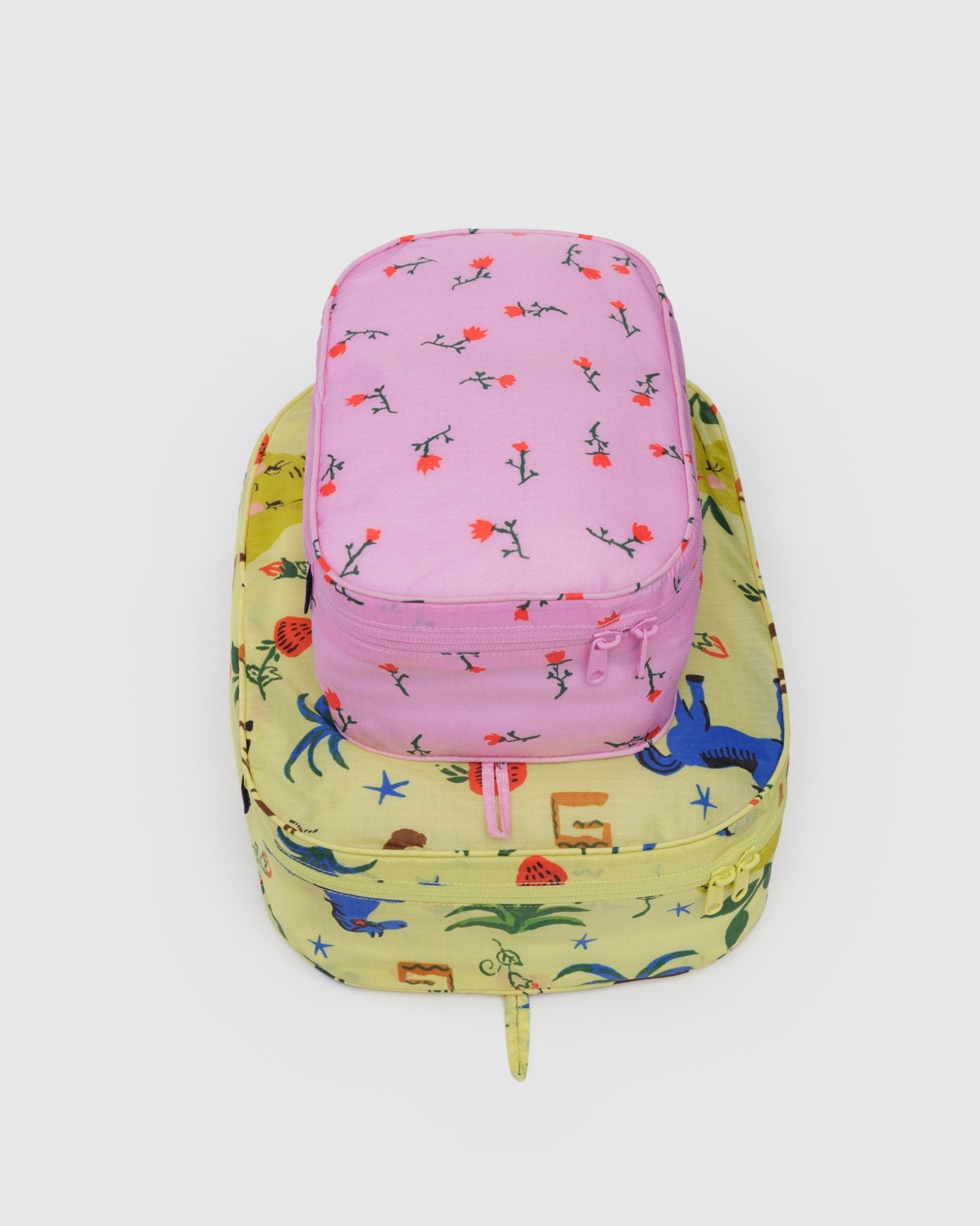 Set of 2 packing cubes, small pink floral-pattern and a medium yellow with fruit and horse design