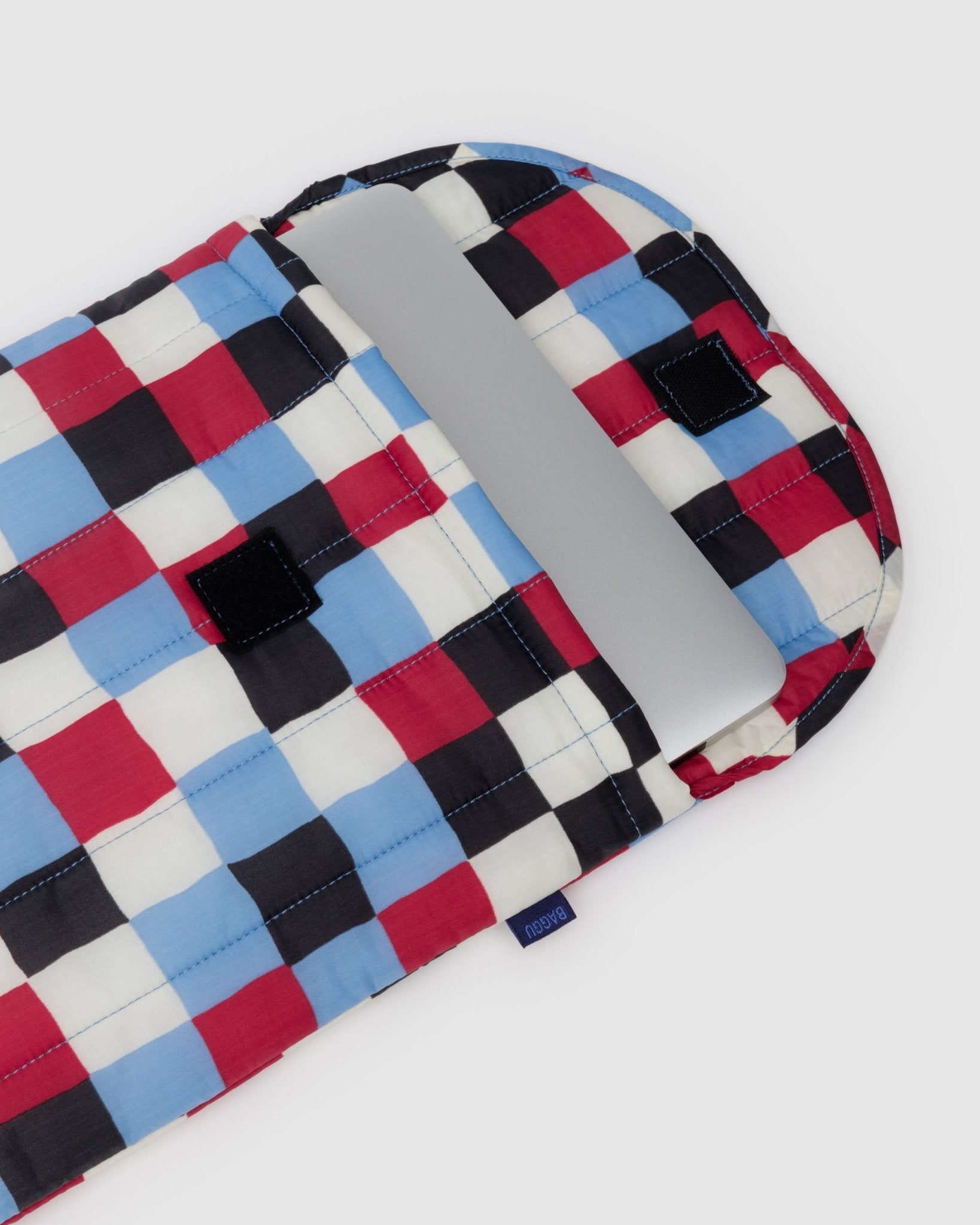 Checkered fabric laptop bag with velcro closure open with laptop inside