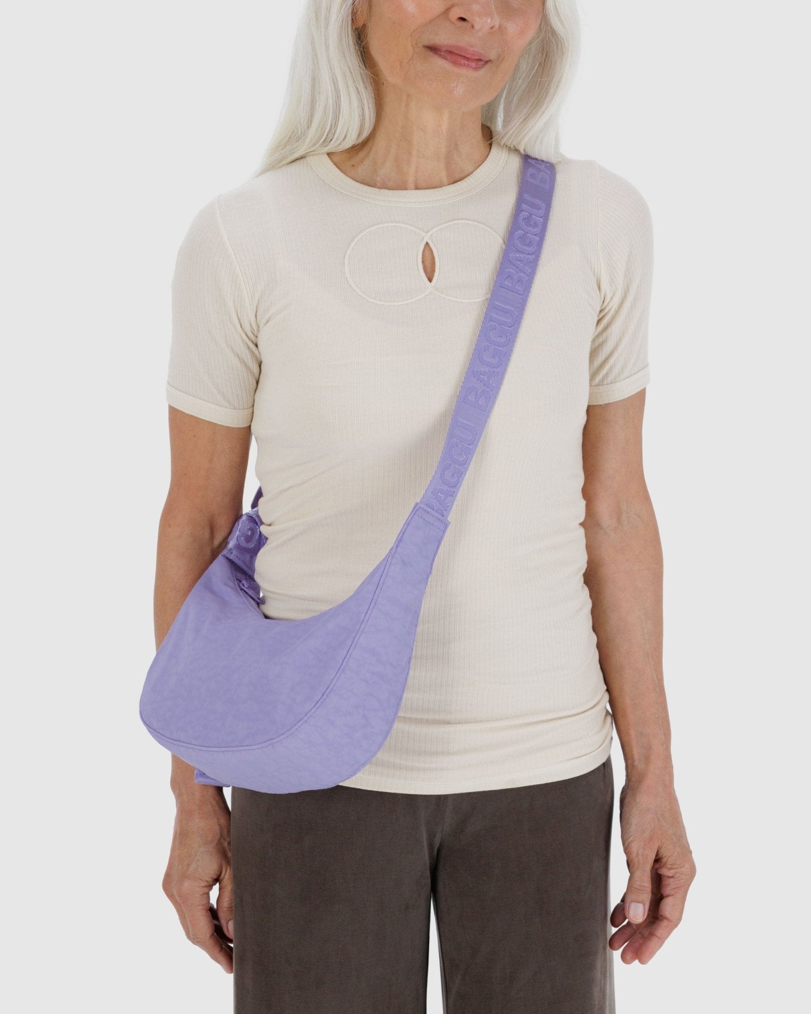 Woman carrying a small crescent purple bag crossbody