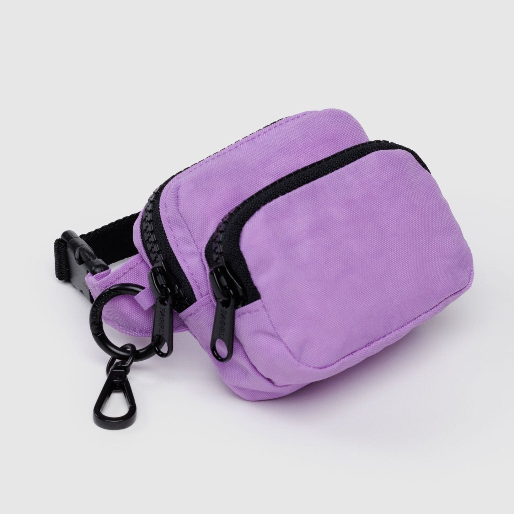 Small purple fanny pack charm with two black zippered pockets, metal keyring with clip and black adjustable strap.