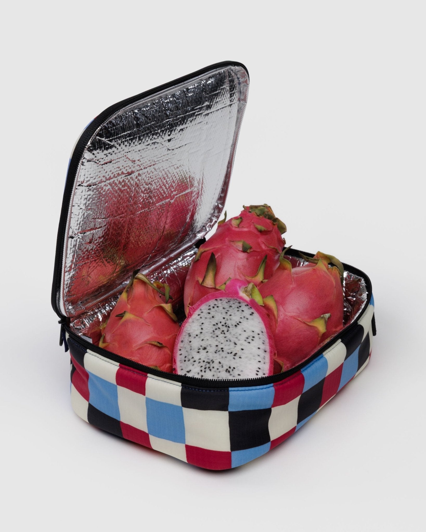 Checkered blue, white, red and black patterned insulated lunch box with dragon fruit inside.