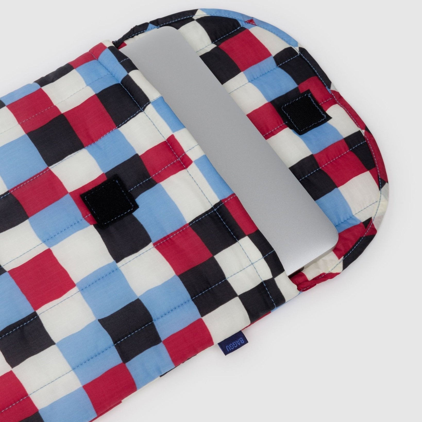 Checkered print nylon laptop bag with velcro closure open with laptop inside.