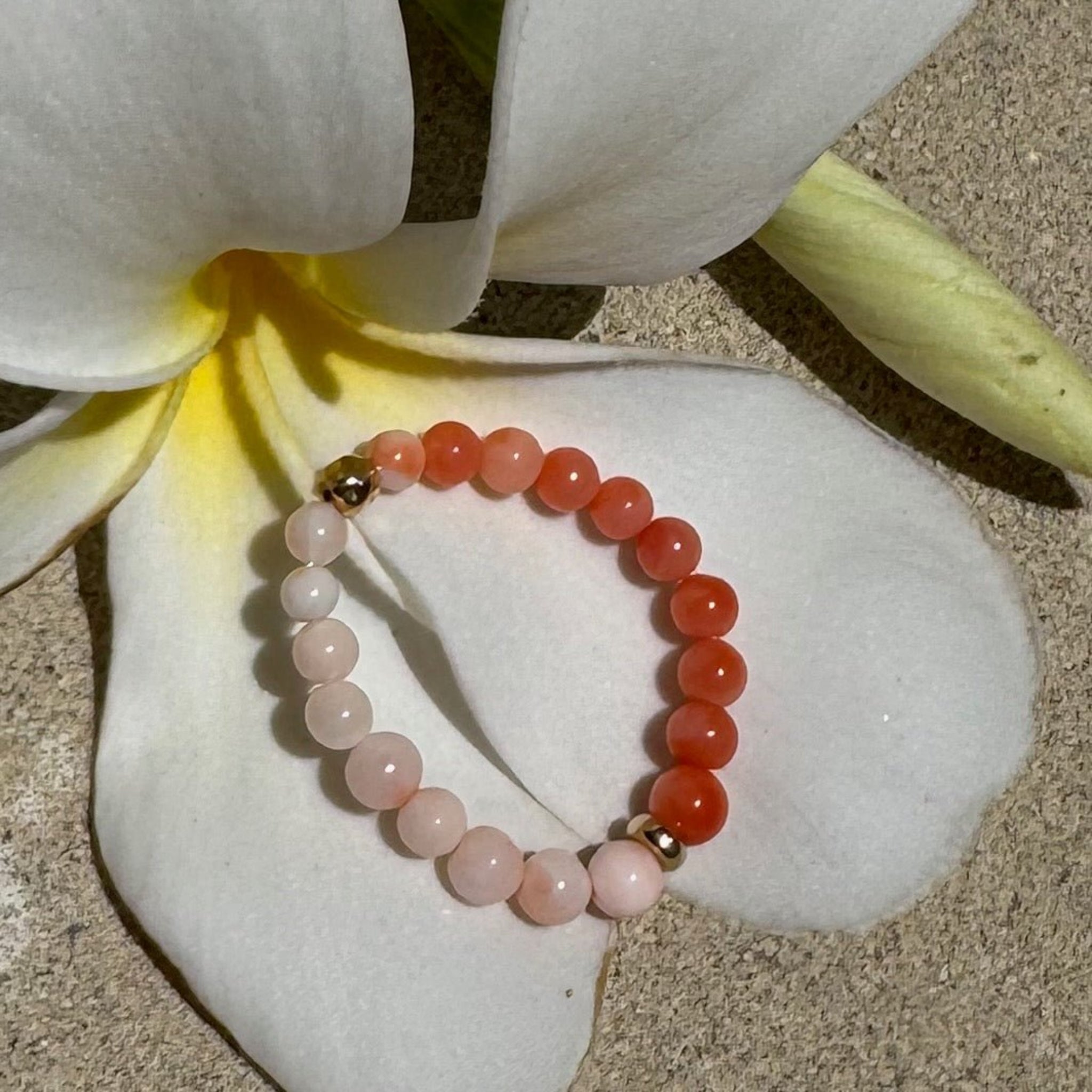 Bead Stretch Ring of Momo Coral and Angel Skin Coral sitting in a frangipani flower.