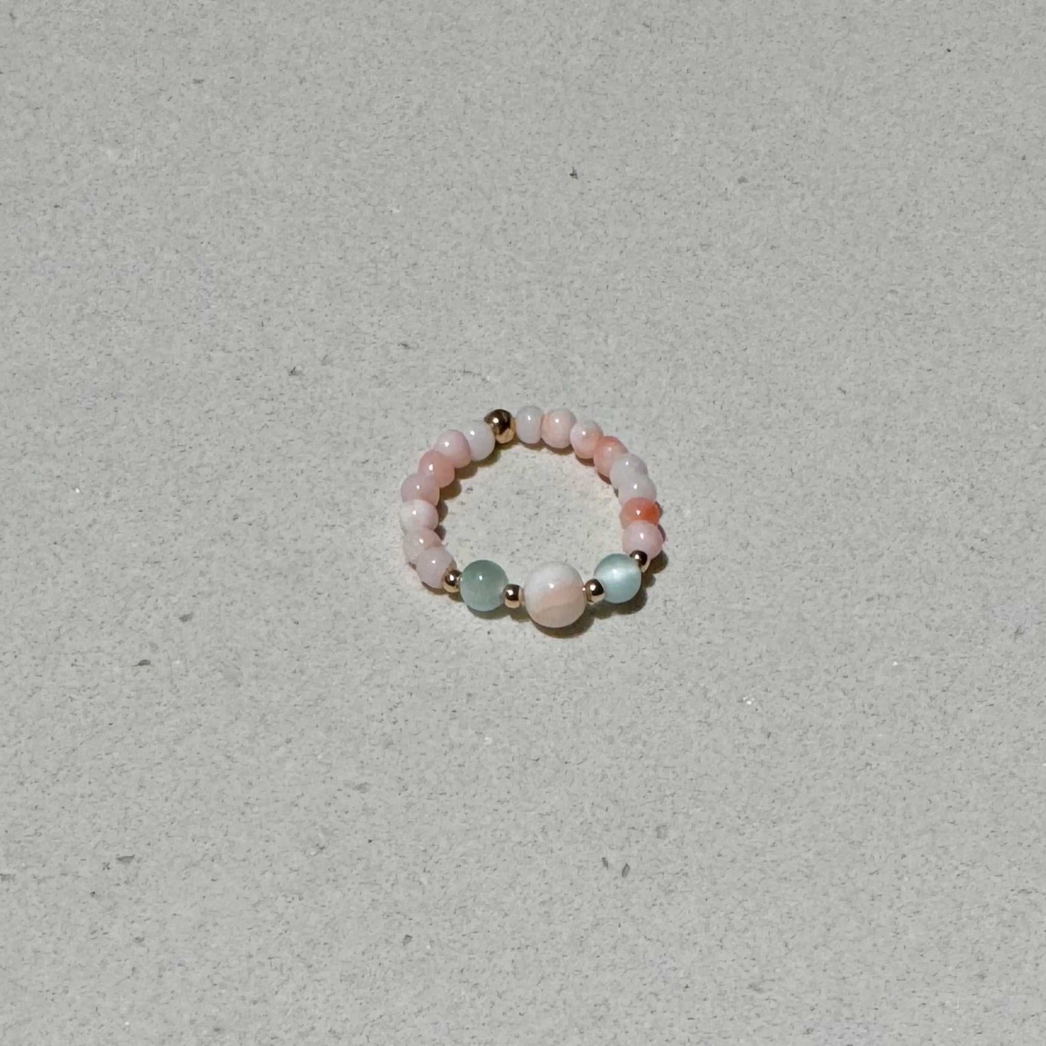 Bead Stretch Ring of natural stones and angel skin coral on a bench