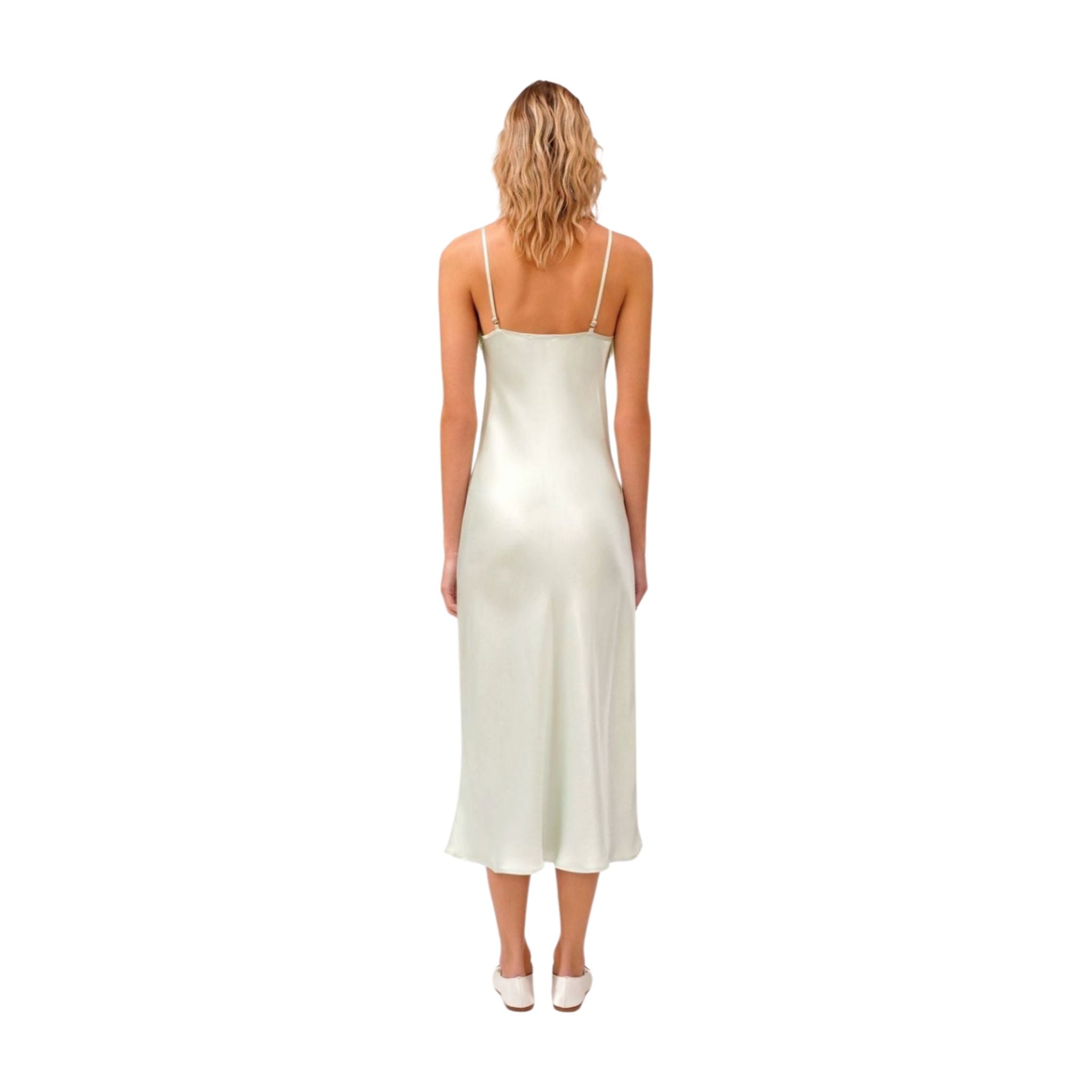Woman wearing a mint satin slip dress with adjustable spaghetti straps.
