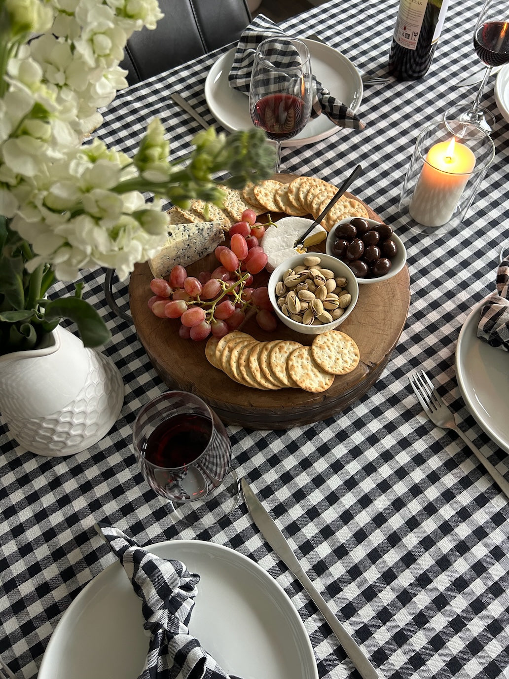 charcoal-gingham-tablecloth-dining-setting-with-food-platter-glasses-of-wine-flowers