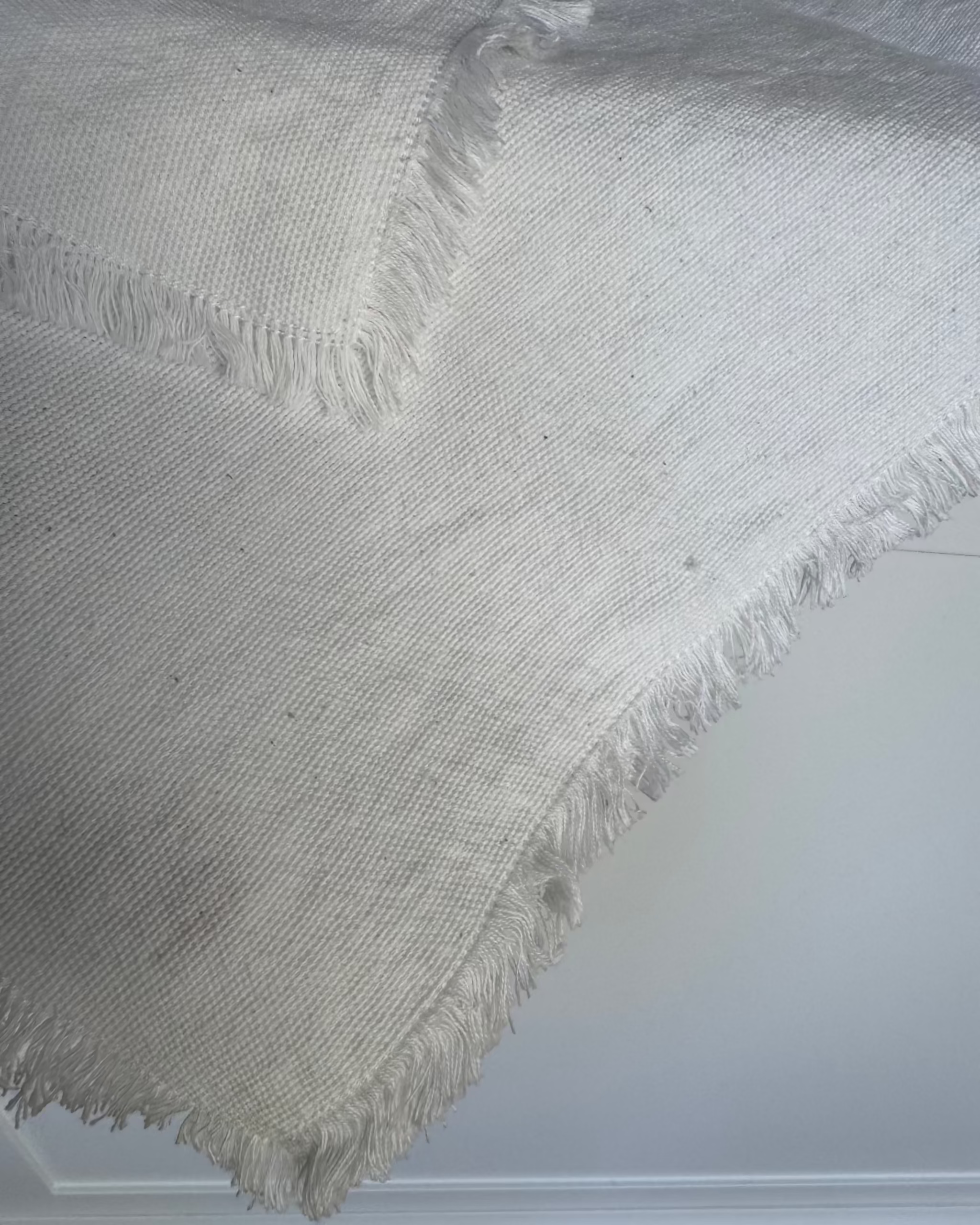 White cotton napkin with frayed edges over the edge of a table