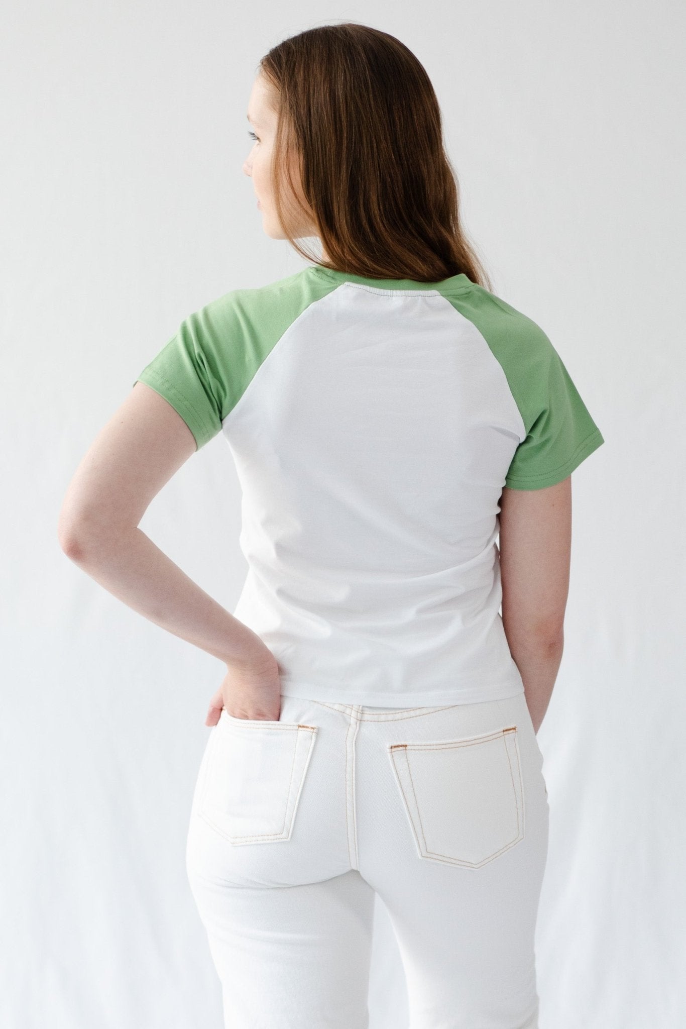 Back of a woman wearing a white t-shirt with green short sleeves.