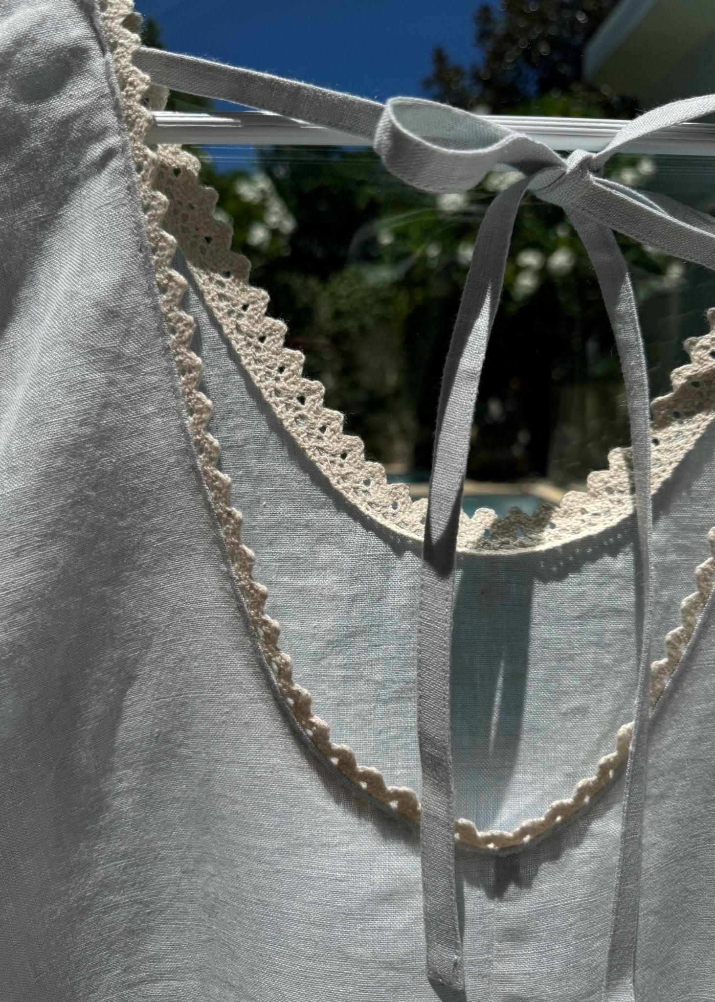 Close up of back ties of a light blue playsuit on hanger - ANNIE.G